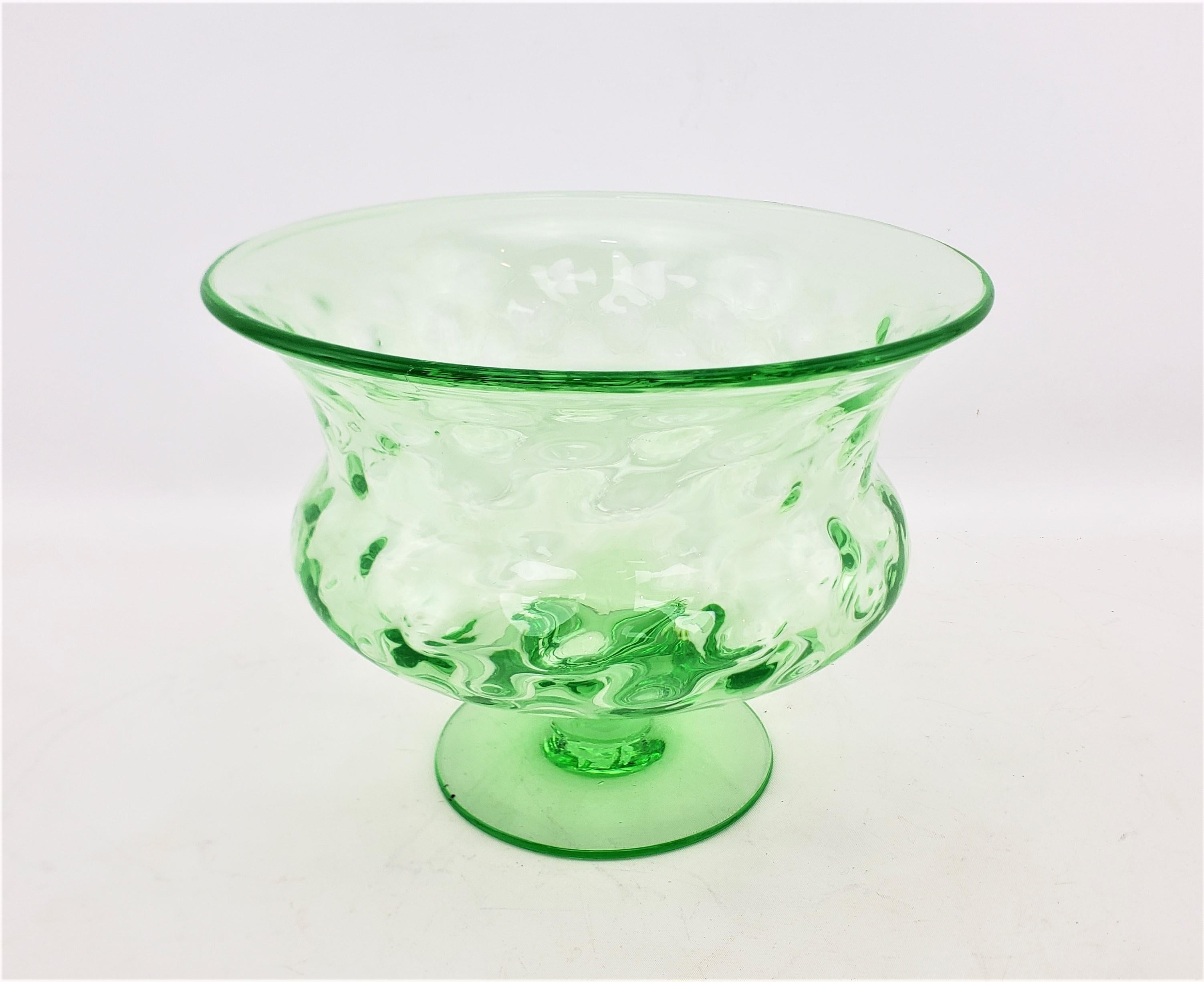 This antique pedestal bowl is unsigned, but presumed to have originated from the United States, and date to approximately 1920 and done in a Victorian style. The bowl is done with uranium green glass and has a flared rim, with raised bulbous