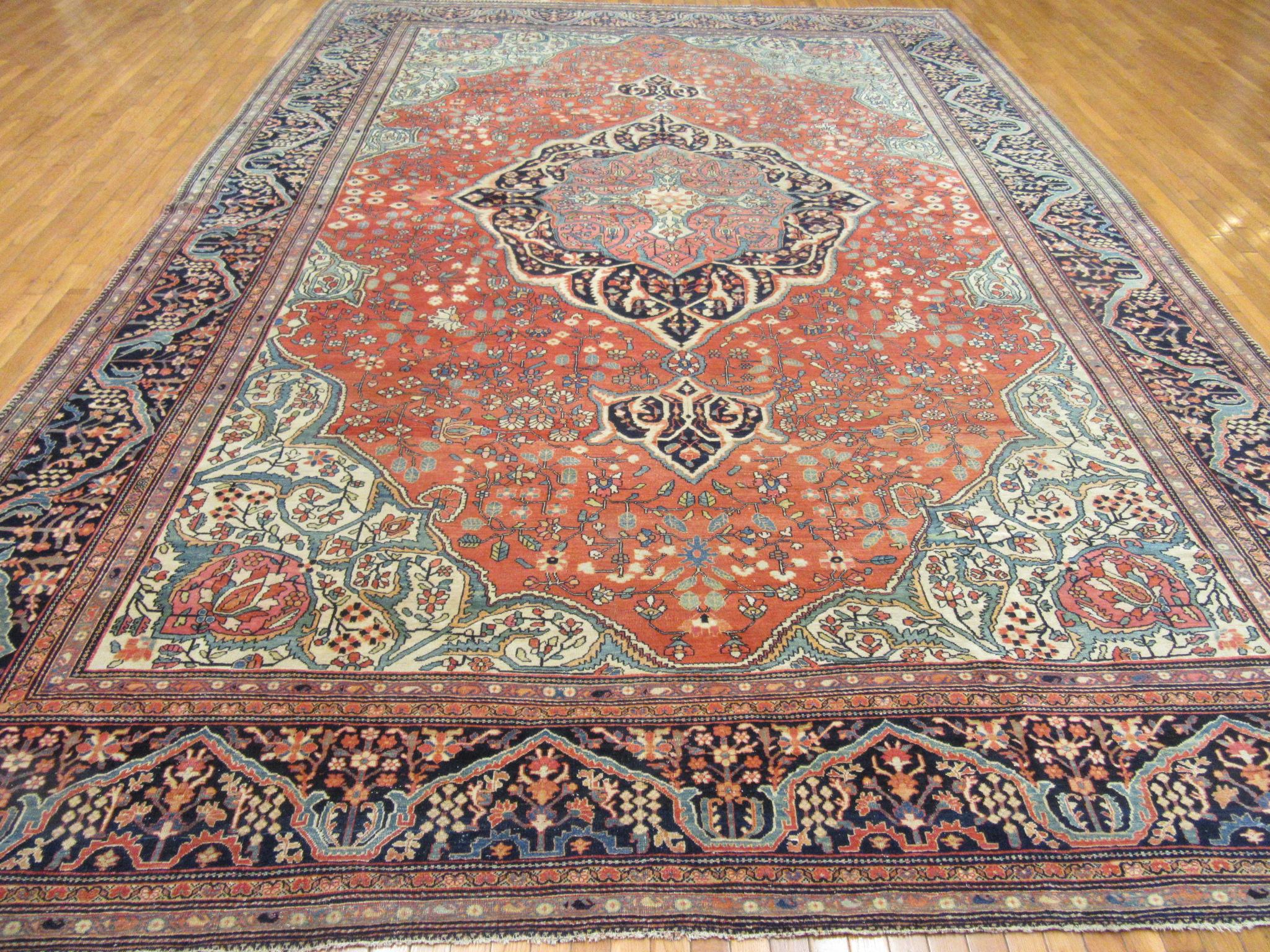 This is an antique hand knotted Persian Sarouk Farahan rug. It is made with wool colored with natural dyes on a cotton foundation. It has a fine uniform weave and an elegant traditional central and corner medallion design. It measures 10' 8'' x 15'