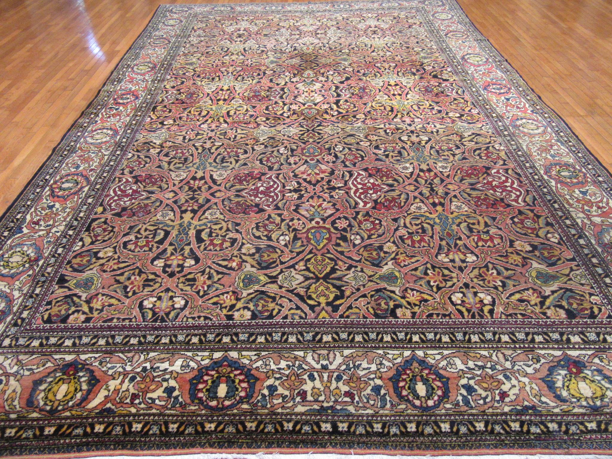 This is an antique hand knotted Persian rug from the infamous city of Isfahan. It is made with wool on cotton foundation with a typical fine weave from this region. The rug has an all-over seventeenth century Eslimi design on a dark navy color