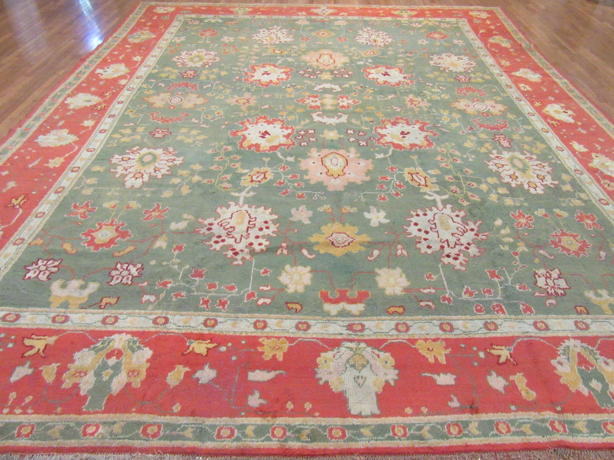 This is an antique hand knotted rug from Turkey. It is made with wool on a cotton foundation in the village of Oushak with rich primary colors in a simple all-over pattern on a green color field and red border. It would enhance the look of any