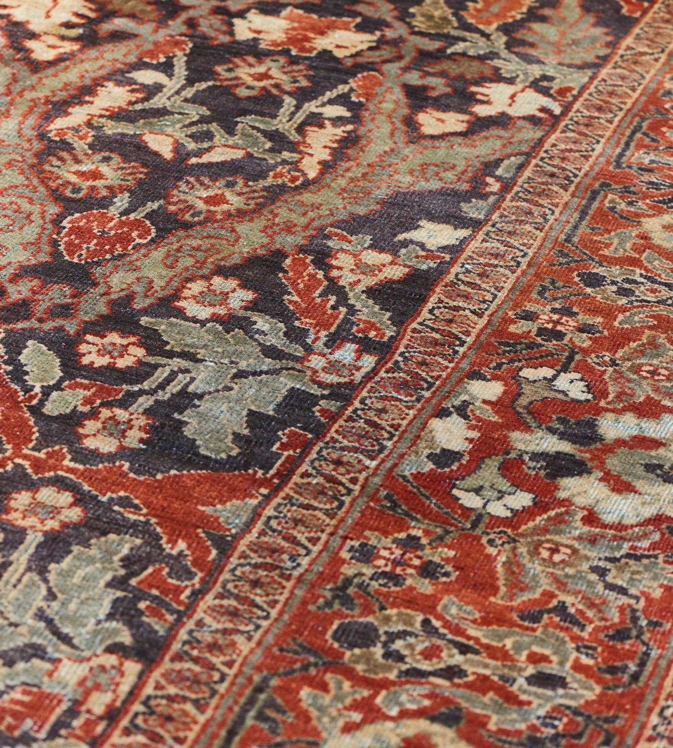 This antique Sultanabad rug has a deep chocolate-brown field with an overall design of bold pale green vine issuing a delicate floral vine around a central column of brick-red spandrels containing a bold central floral motif issuing a variety of