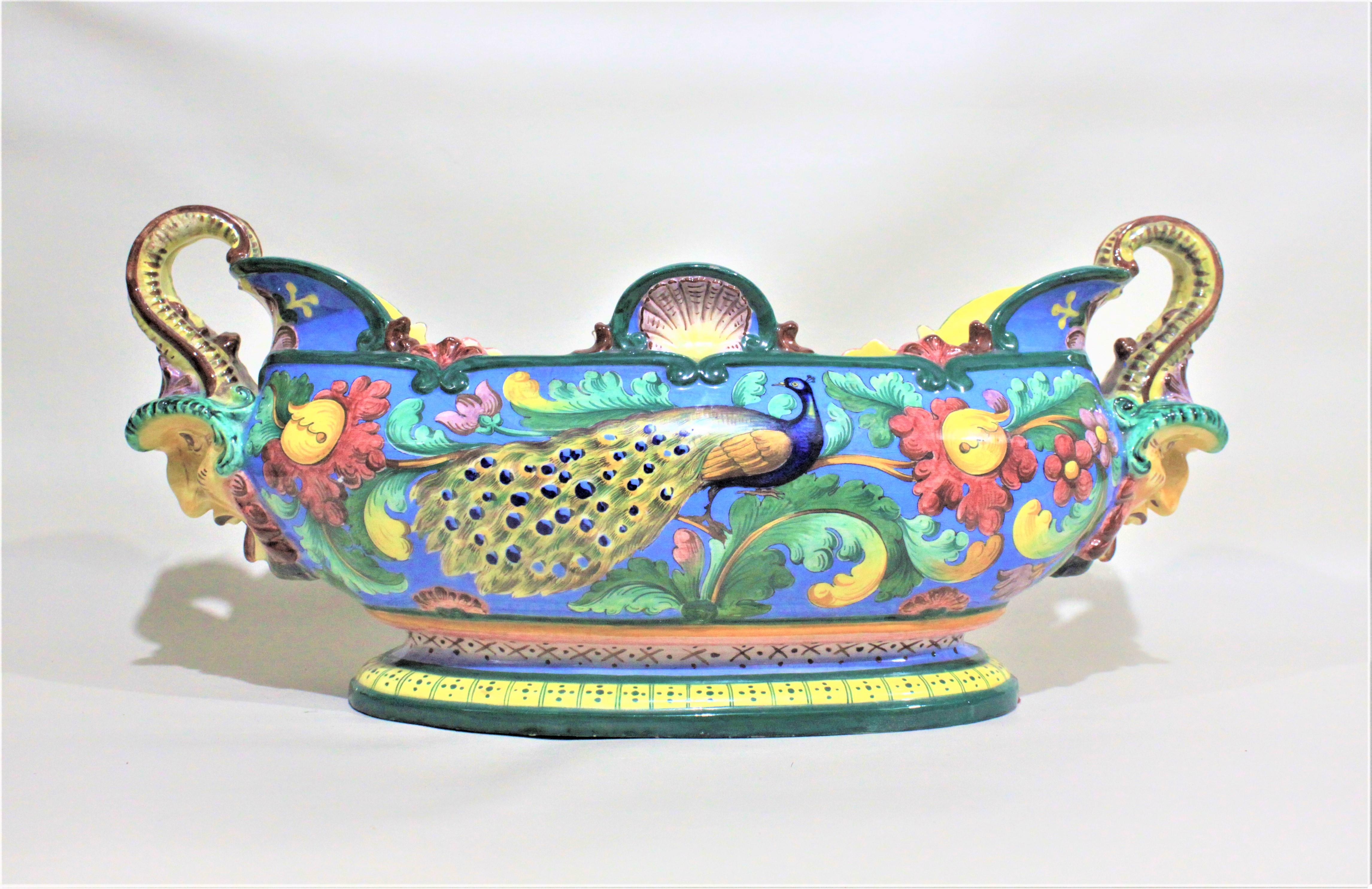 This very large and very colorful Italian Majolica centrepiece bowl was made between 1900 and 1920 in the Renaissance Revival style. The sides show hand painted blue peacocks surrounded by flowers and foliage in extremely vivid colors. The handles