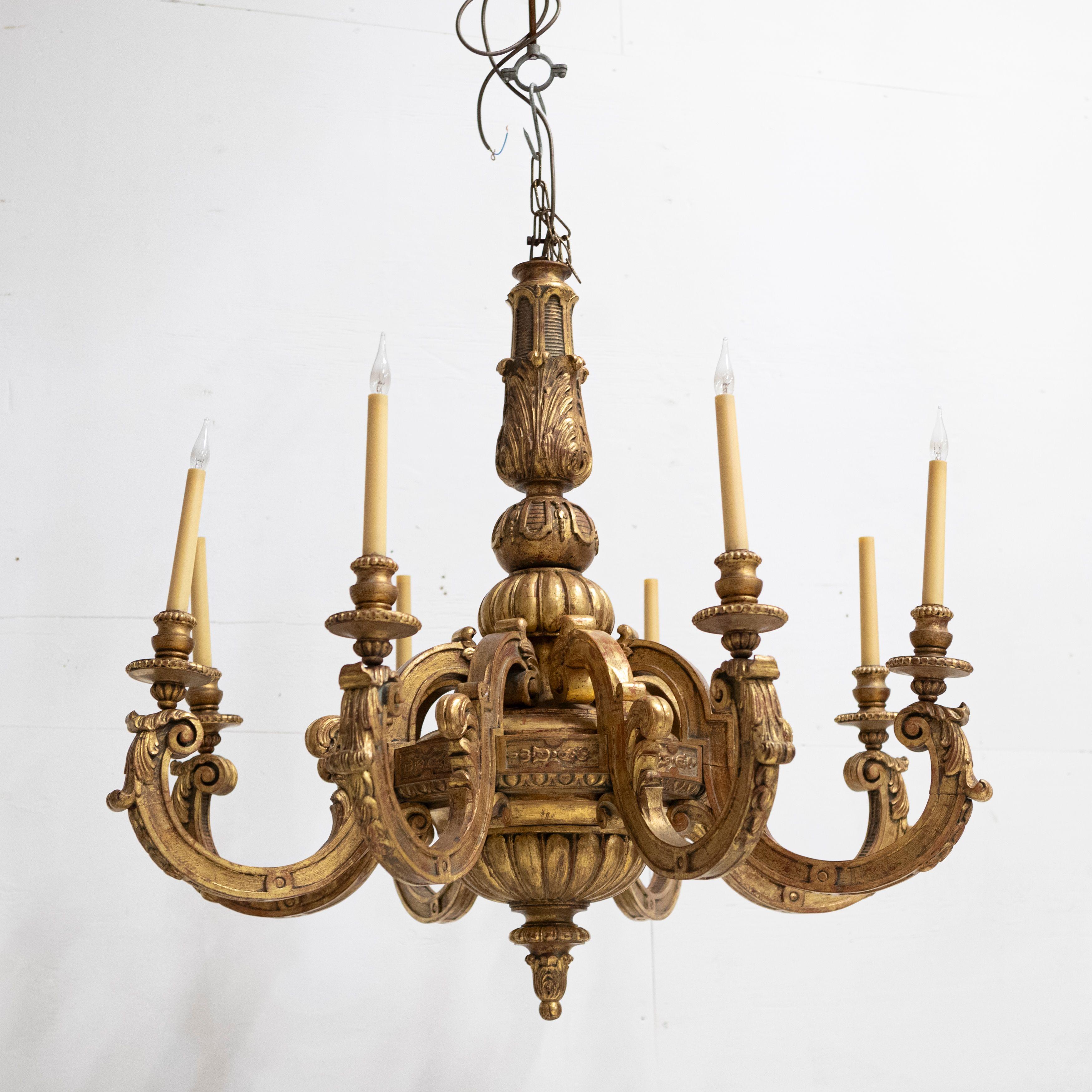 This large mid-19th-century chandelier is composed of 8 ornate giltwood S shape arms.

The intricate detailing throughout this carved piece provides an opulent light feature.

Decorative foliage adorns the scrolling arms with trumpet bobeche drip