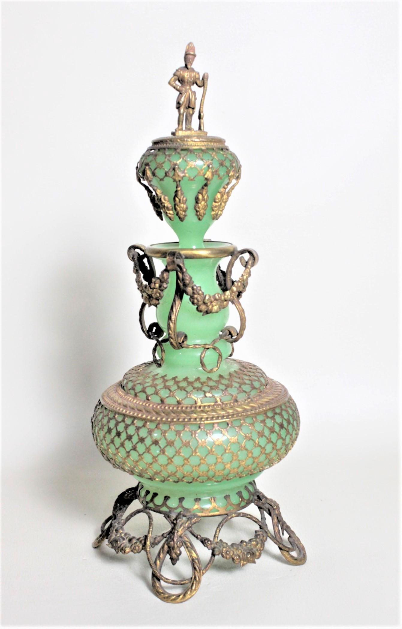 This large antique perfume bottle is unsigned, but presumed to have been made Bohemia (Austria or the Czech Republic) in circa 1880 in the Renaissance Revival style. The bottle itself is made of jadeite green glass as is the stopper which is