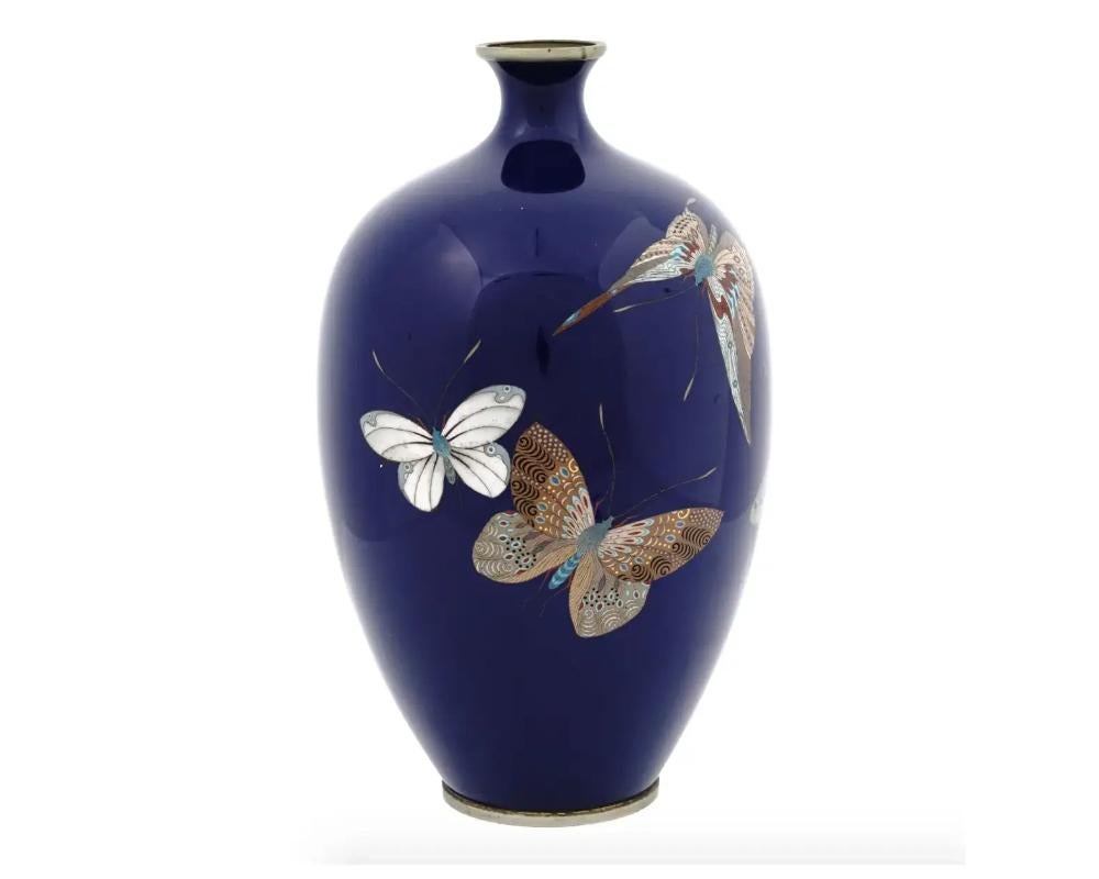 A large antique Japanese Meiji period enamel vase. The vase has an amphora shaped body and a narrow neck. The vase is enameled with a polychrome image of butterflies made in the Cloisonne technique on cobalt blue ground. Probably numbered on the