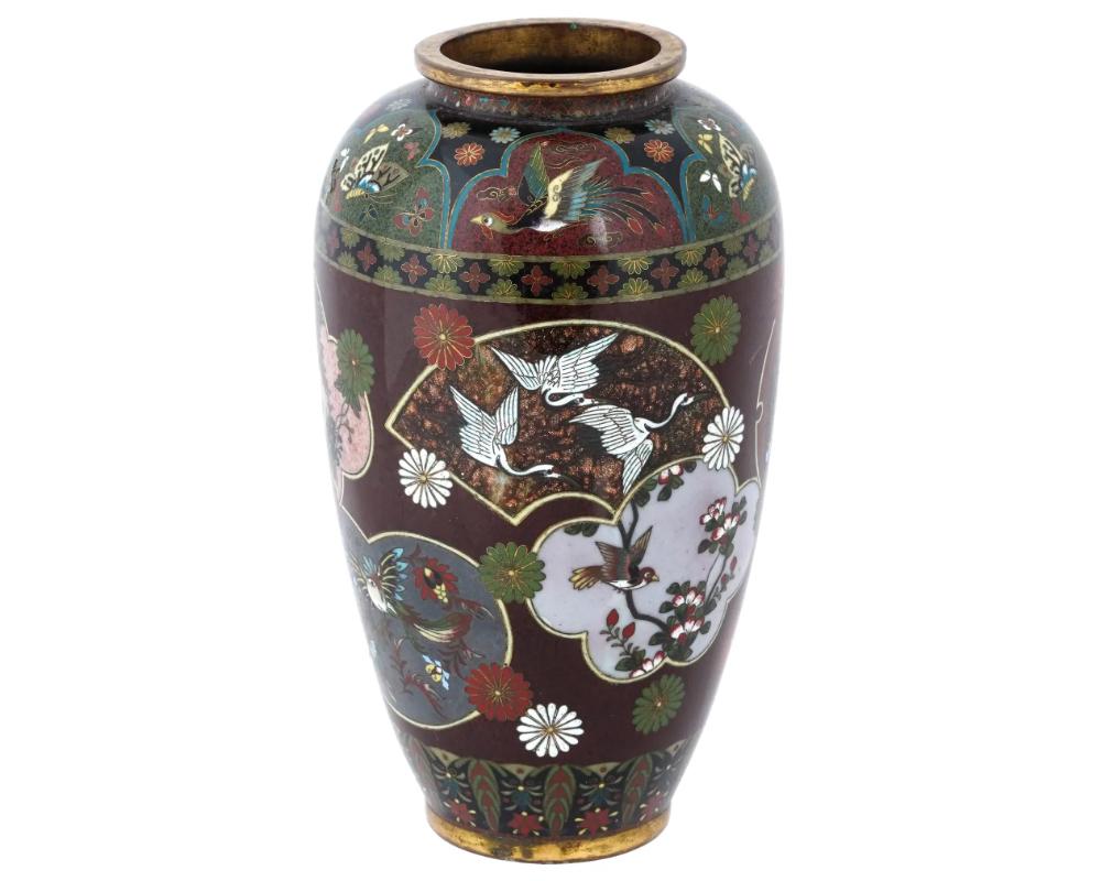 A large antique Japanese Meiji period vase attributed to Kyoto Shibata. Features vivid depictions of birds and floral motifs, showcasing the meticulous application of cloisonne enameling, with gilt brass outer rims. The Meiji era was a time of