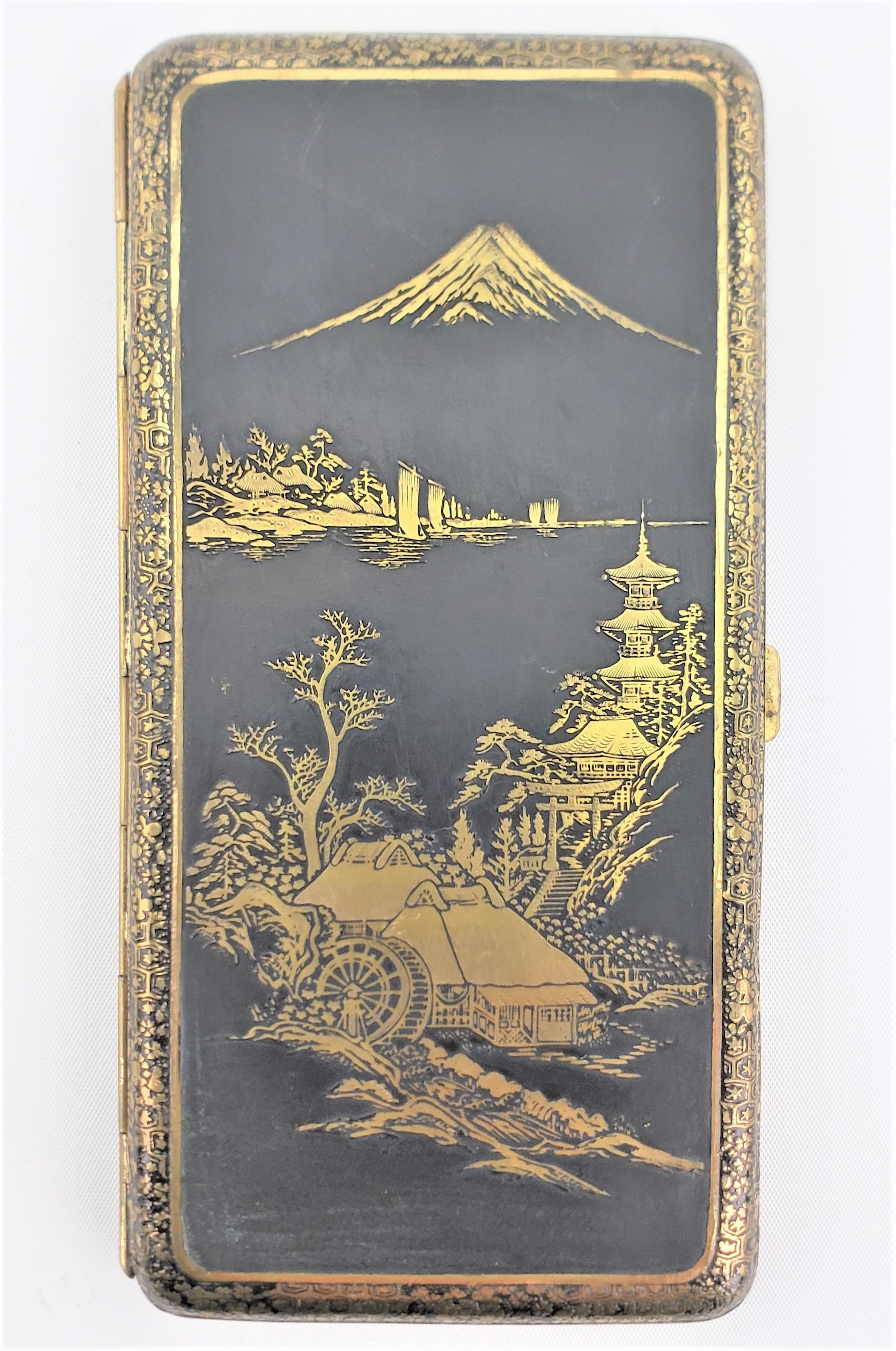 This large antique damascene styled tobacco case is unsigned, but presumed to have originated from Japan and dating to approximately 1920 and done in a Anglo-Japanese style. The case is made of metal which has been ornately engraved with a Japanese