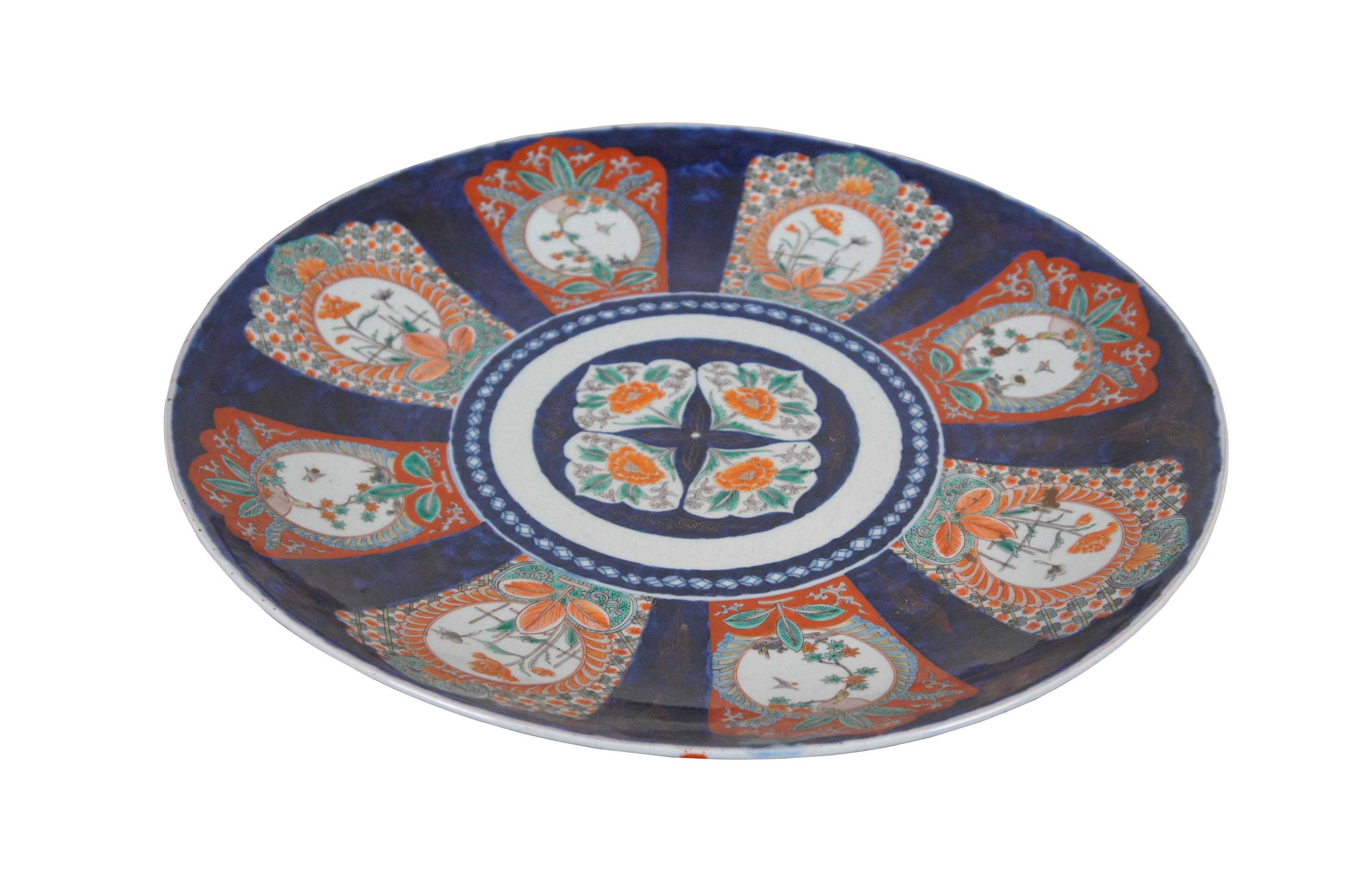 Très grande et impressionnante assiette / chargeur / plat en porcelaine Imari de la période Meiji, peinte à la main de scènes florales polychromes / bordures en orange / rouge, bleu cobalt, vert et or.

Dimensions :
21,75