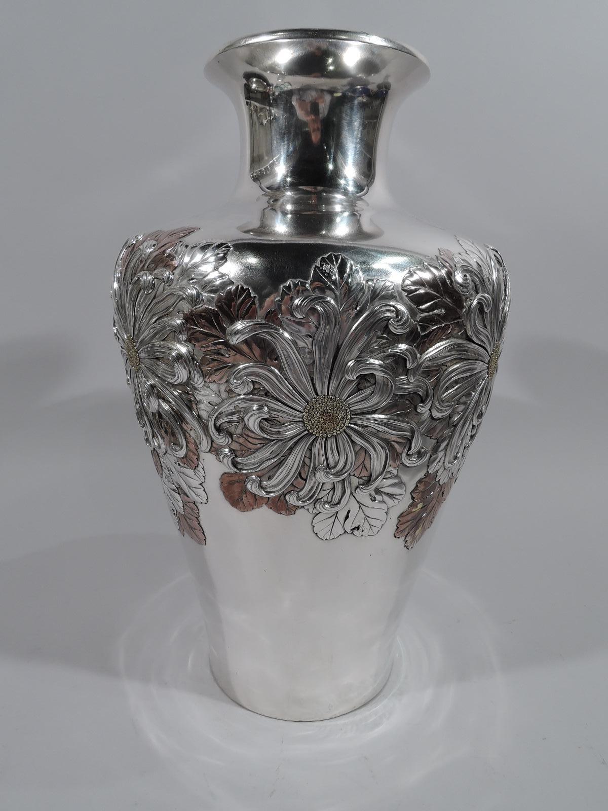 Large Japanese mixed metal on silver vase, circa 1880. Tapering with round shoulder and short spool neck. Applied ornament in silver, gold, and copper: Chrysanthemums—big bold blooms with fluid whiplash petals—on overlapping leaves. Wonderful