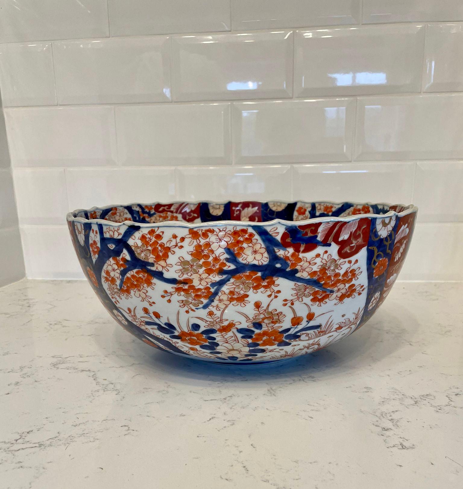 Large antique Japanese quality Imari bowl having a scalloped shaped edge with wonderful hand painted flowers, leaves and trees in red, blue, green, white and gold colours 

15 x 34.5 x 34.5cm
Date 1900.

 