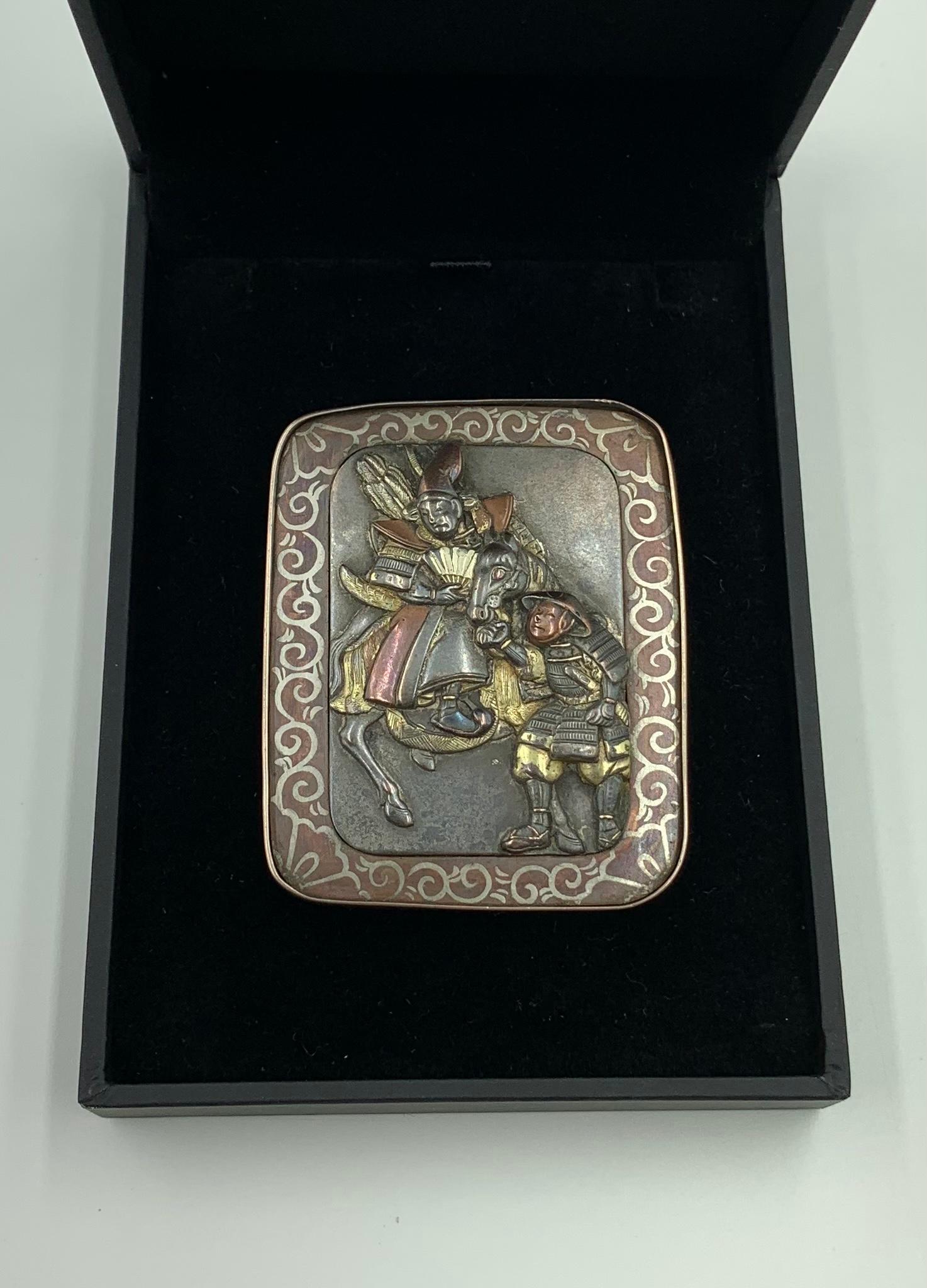 Fine antique beautifully detailed Japanese Shakudo brooch of a Samurai warrior on a horse being held by a groom. Intricately detailed, the Samurai is depicted in full regalia and holding a fan in his right hand, his right foot in an ornate stirrup