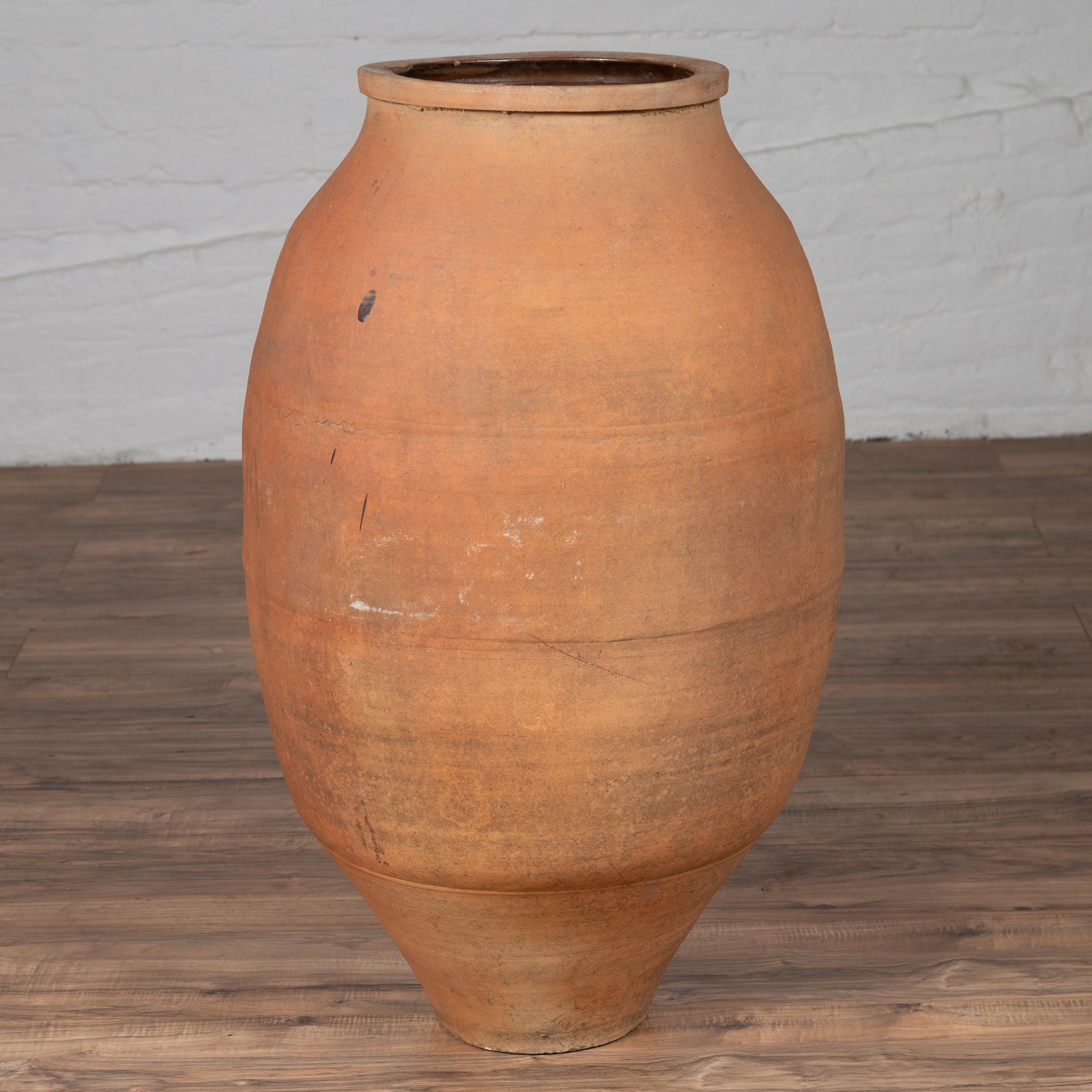 A tall antique Japanese Shigaraki stoneware grain storage urn from the early 20th century with warm patina. Born in one of the six ancient kilns of Japan, this large Shigaraki urn is made of sandy clay typical of the region, and features a rounded