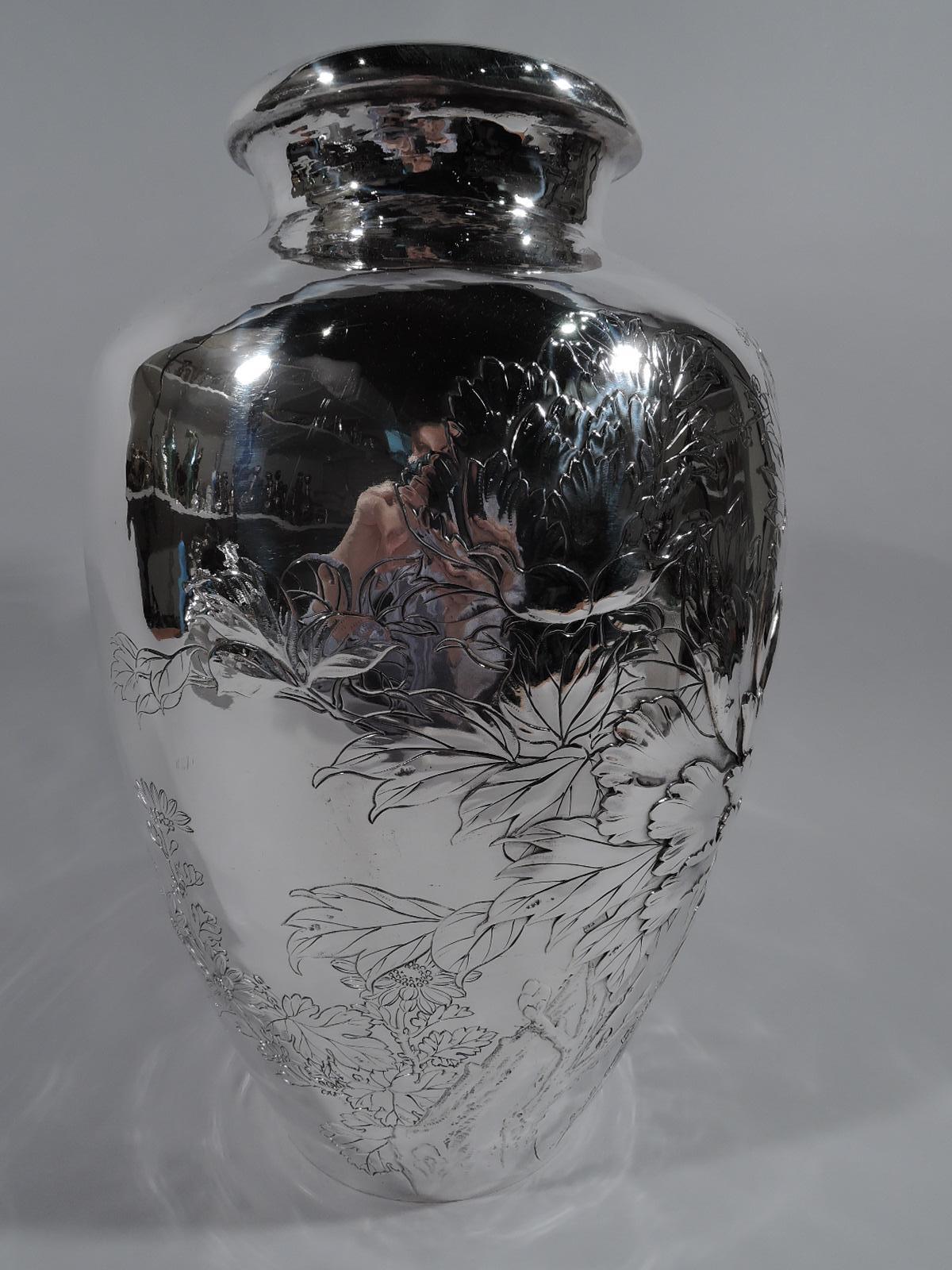 Large Japanese silver vase, circa 1910. Ovoid with short neck and turned-down rim. On front chased chrysanthemum flower heads with veined, serrated, and overlapping petals, blossoming prunus branch, and leaves. The decoration meanders around the