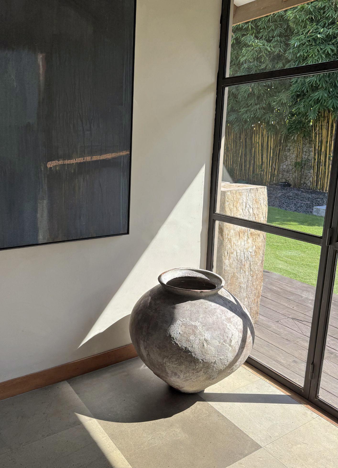 This exquisite antique terracotta water jar from Java is a true testament to the artistry of traditional craftsmanship. Its elegant form and fluid curves give it a sculptural presence that mirrors the essence of modern art. The surface is richly