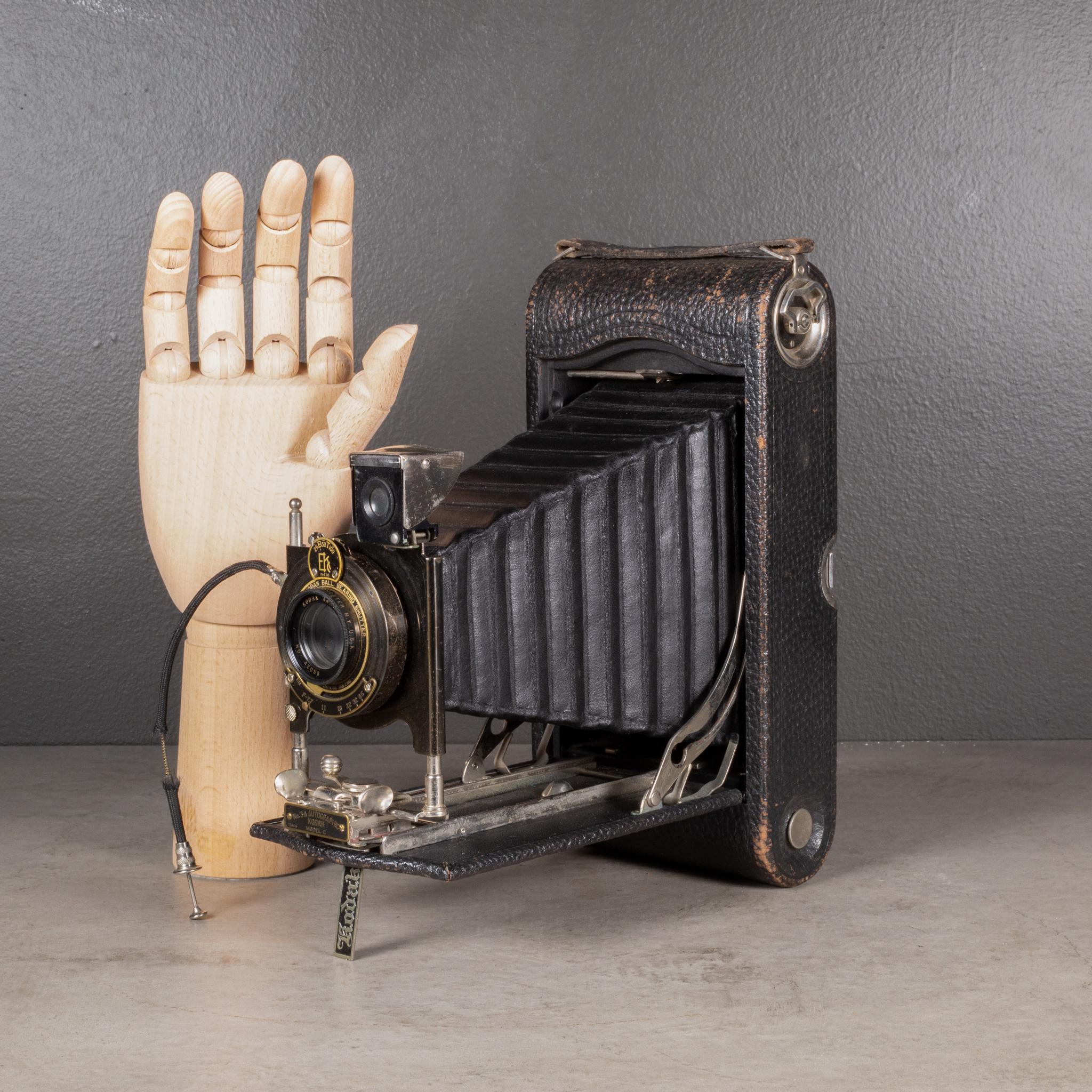 À PROPOS DE

Un grand appareil photo pliant Eastman Kodak No. 3A. Le corps est enveloppé de cuir avec des accents de métal noir, de chrome et de laiton sur la lentille. L'appareil photo est doté d'un cordon pour le bouton d'obturateur à main et se