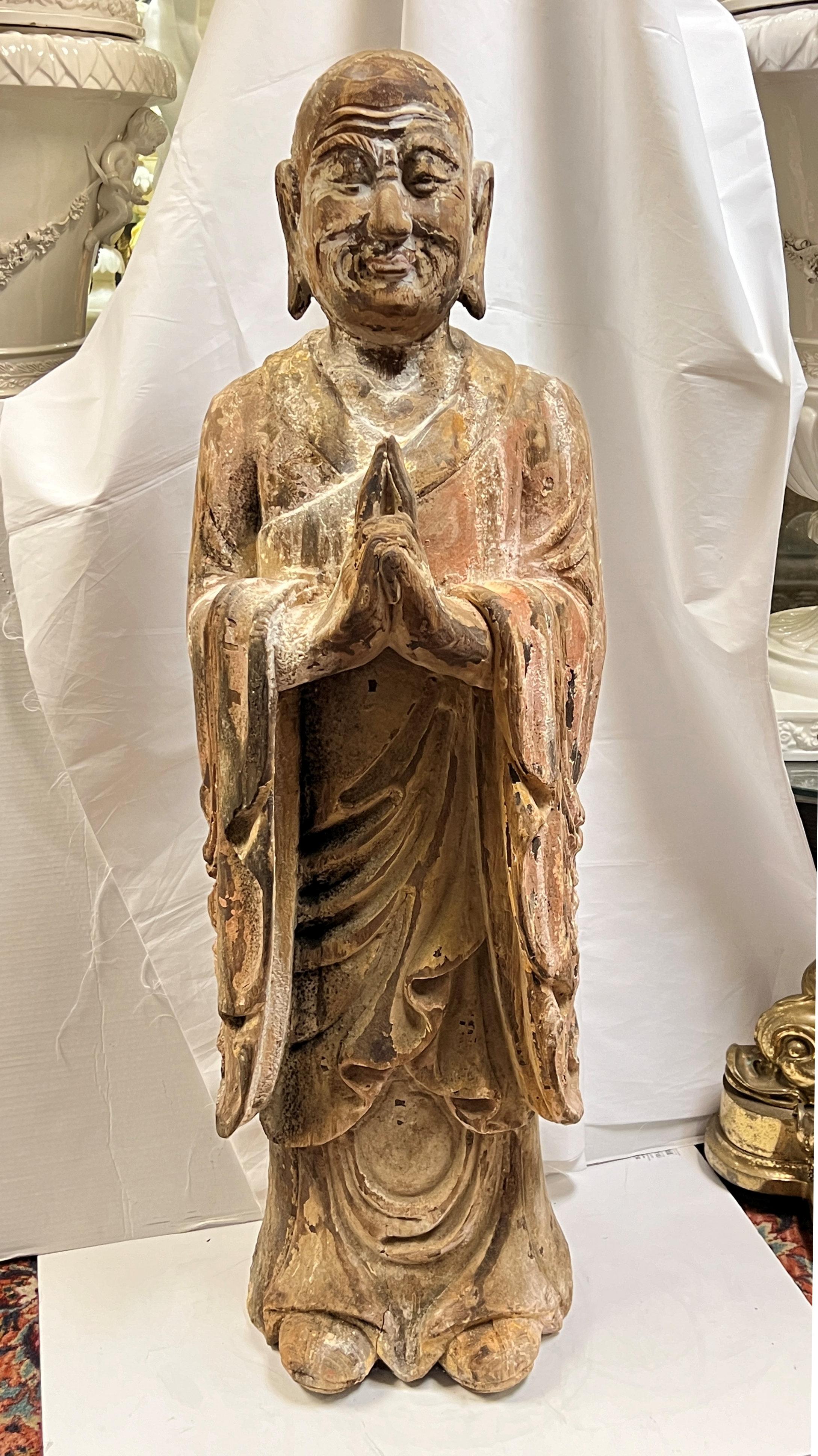 Very large (47 inch tall) sculpture of standing buddha with hands clasped in the gassho gesture, hand-carved from wood with remnants of its original painted finish, Originating in India, the practice of gassho expresses deep honor and respect, and