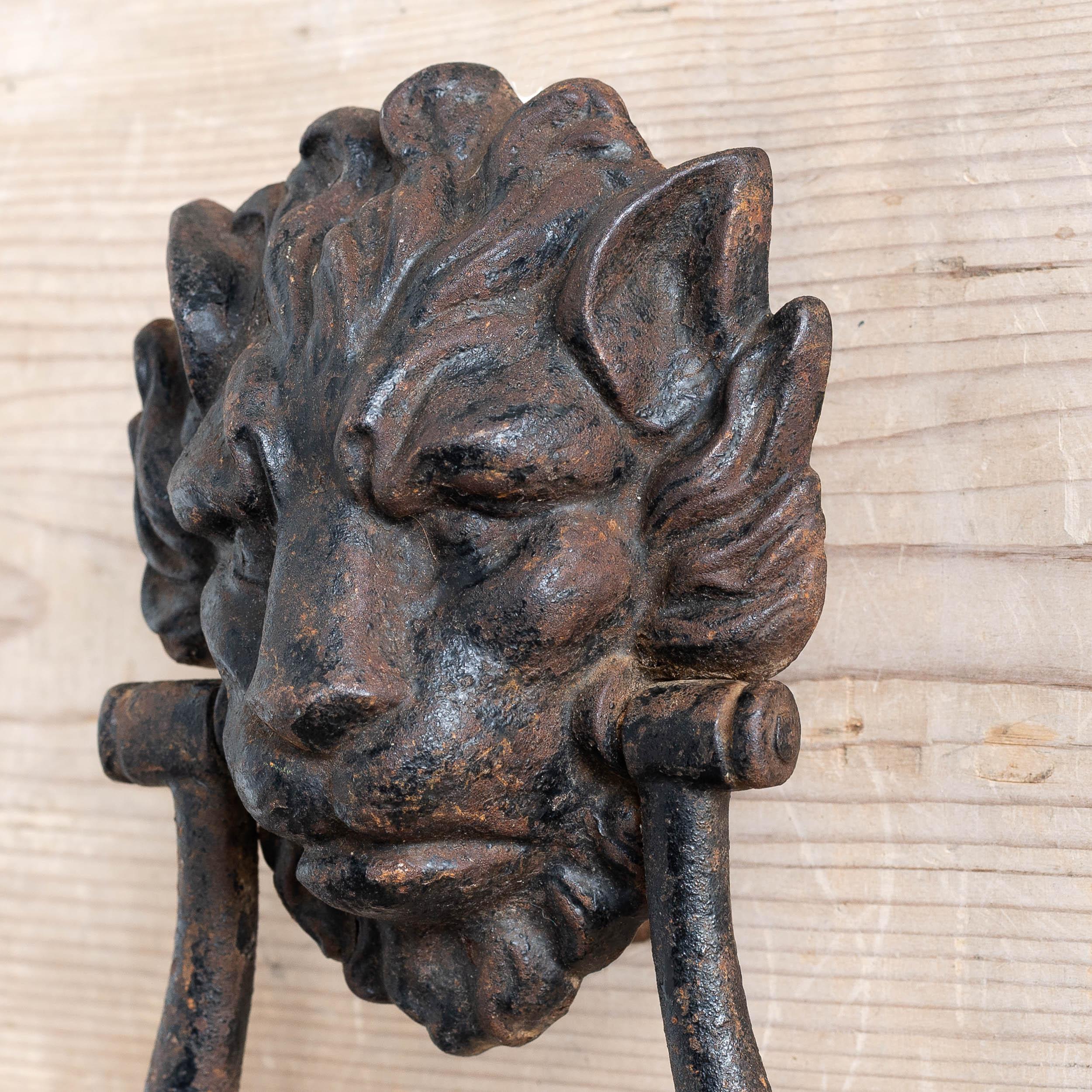A large antique cast iron lion’s mask door knocker, early nineteenth century c.1800-1820,  with knopped rapper and strike plate, in old black paint finish.