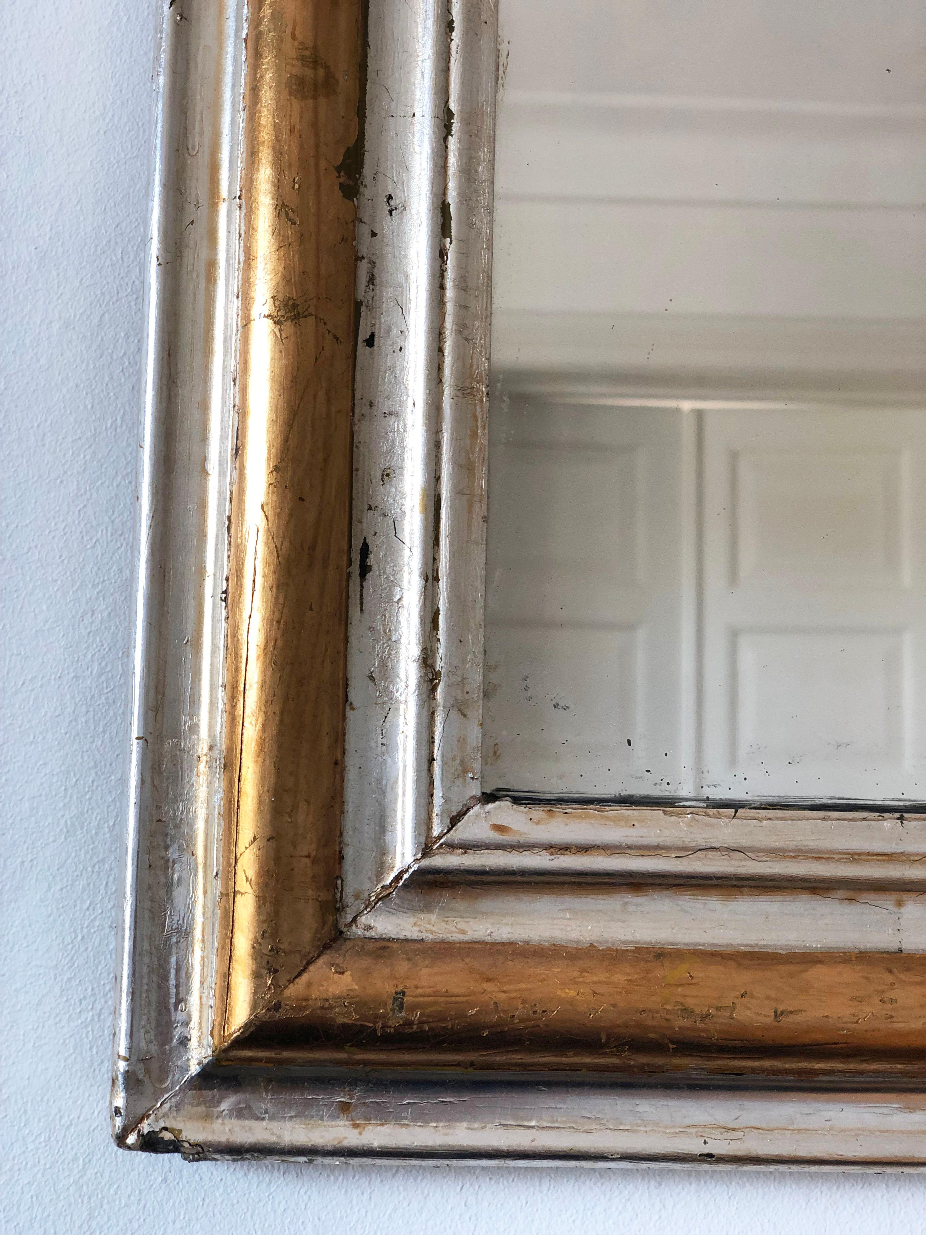 An enchanting antique Louis Philippe French mirror, dating to the late 19th century. The mirror features a refined gilded silver and golden frame and a gracefully curved top, exuding timeless elegance and charm.

Object: mirror
Designer: a French