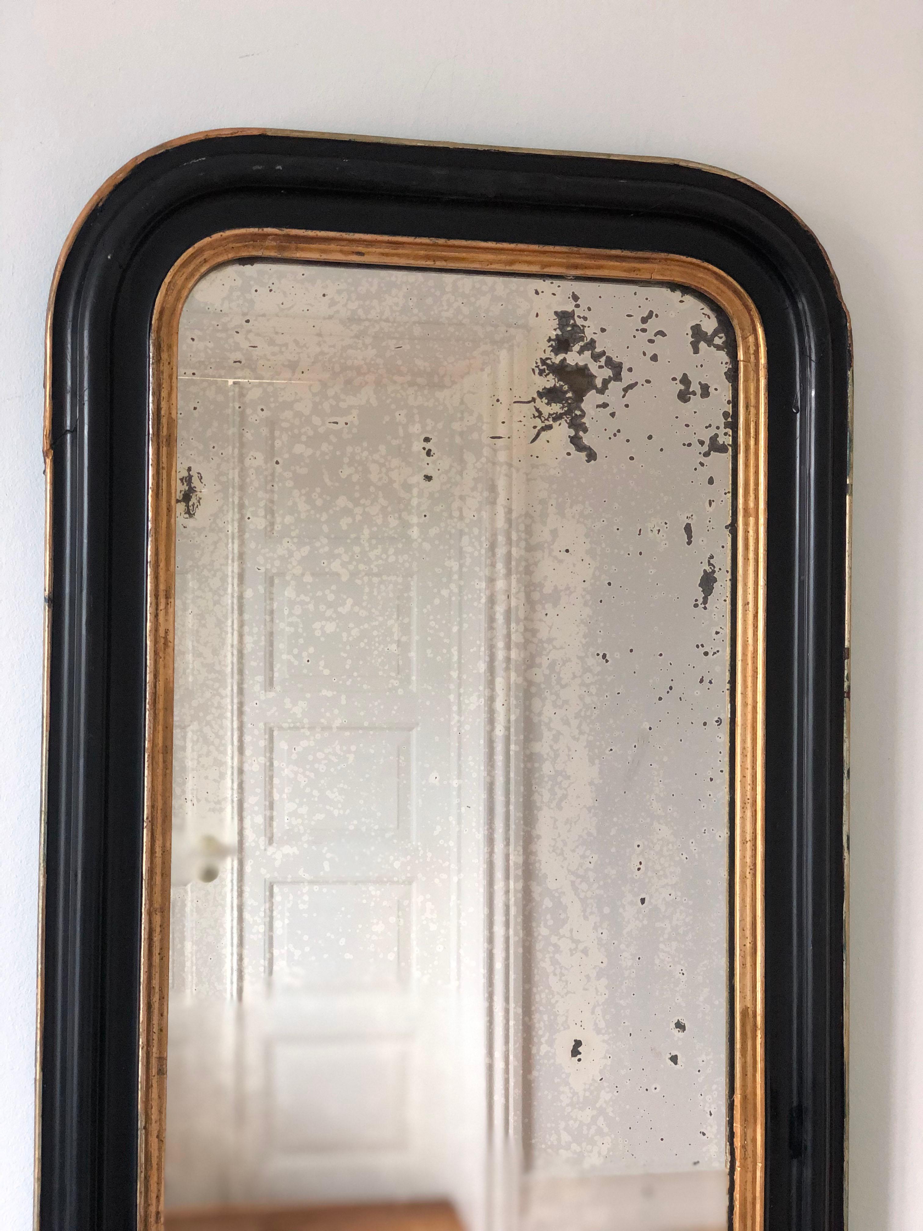 An enchanting full length antique Louis Philippe French mirror, dating to the late 19th century. The mirror features a refined black frame with a soft gold trim and a gracefully curved top, exuding timeless elegance and charm.

Object: full length