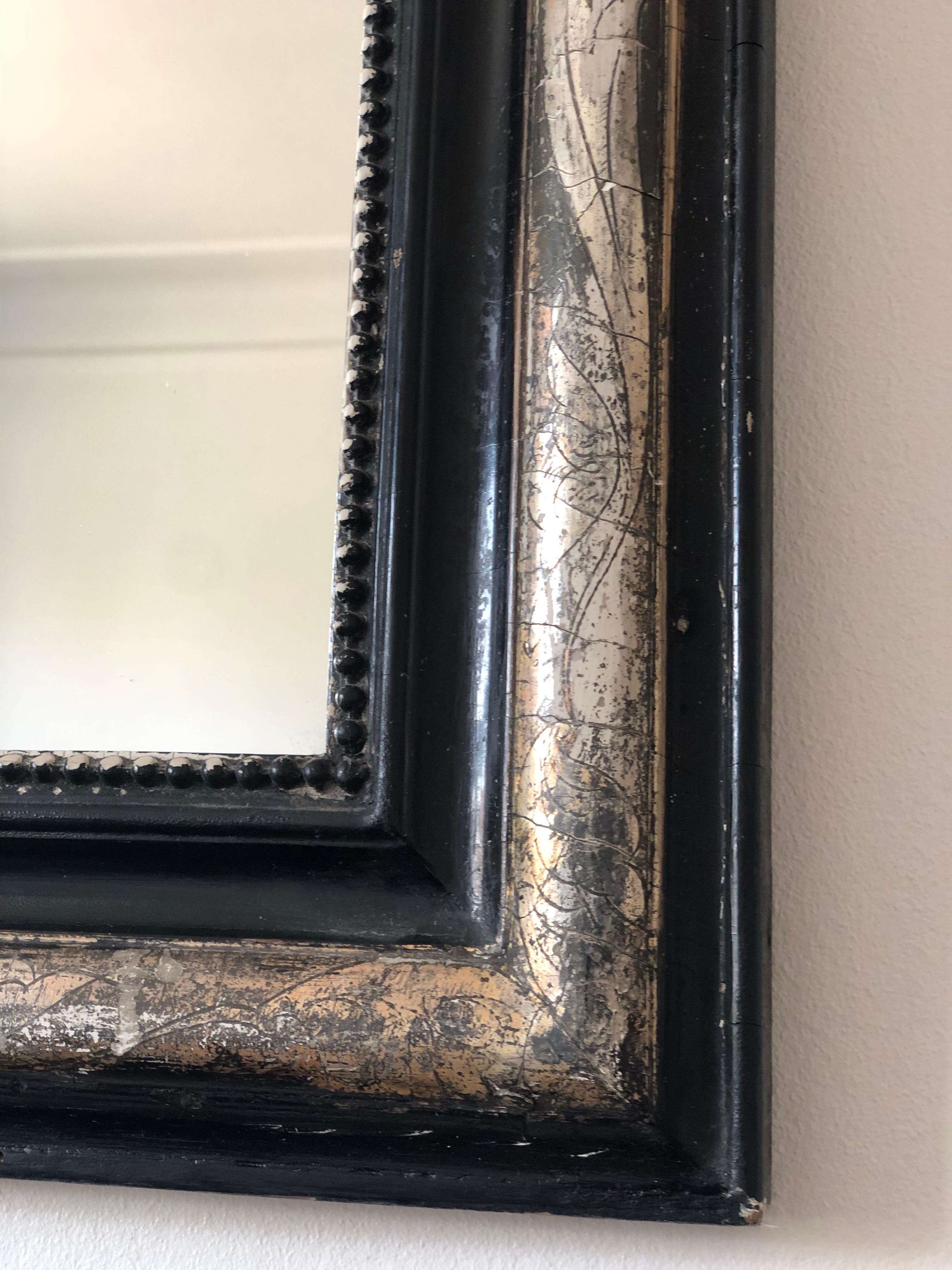 Un antico specchio Louis Philippe proveniente dalla Francia, risalente alla fine del XIX secolo.
Con un aspetto grandioso, la cornice in legno dorato nero e intagliato presenta angoli superiori graziosamente curvati, una bella patina di foglia d'oro