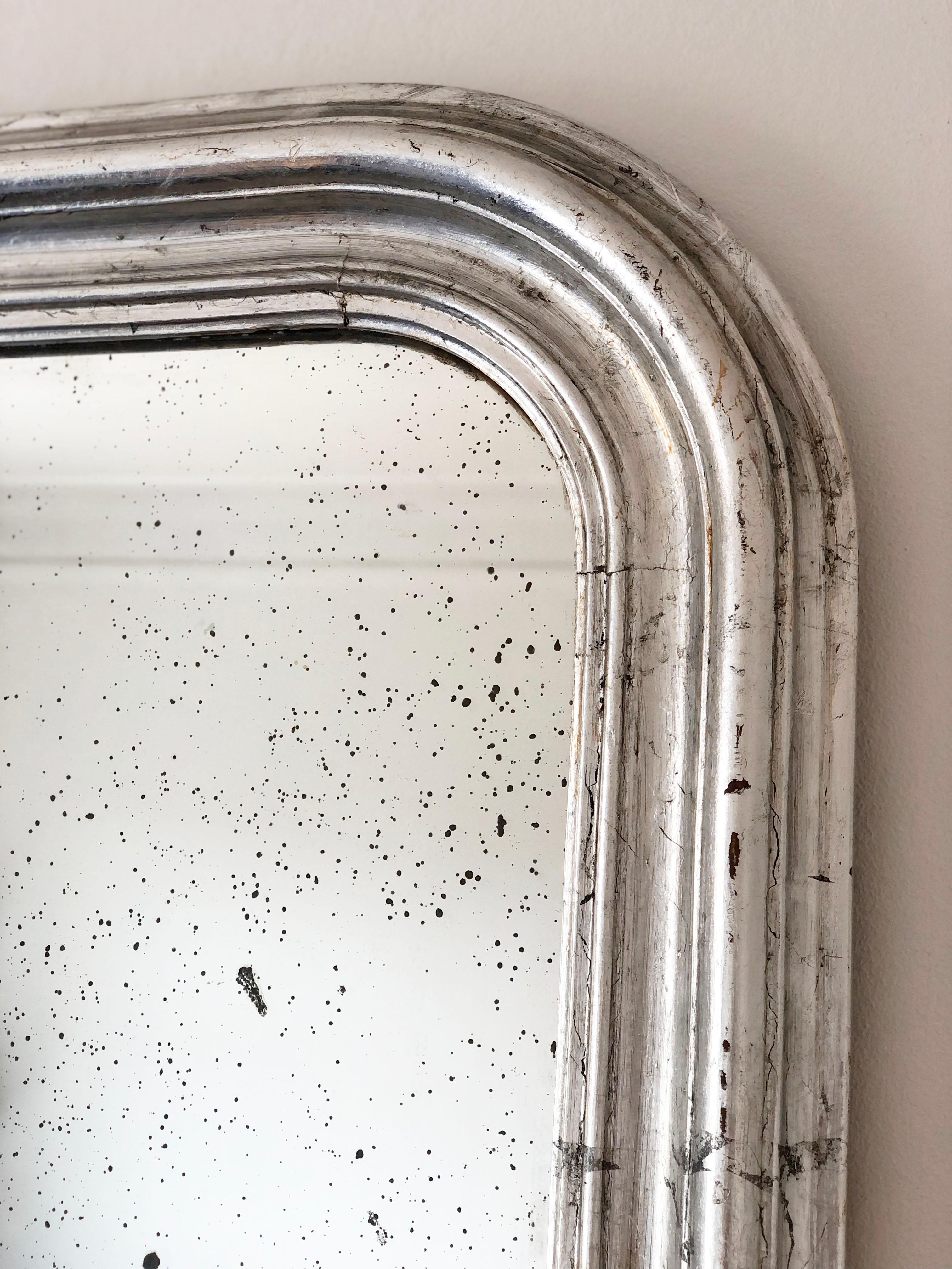 An enchanting antique Louis Philippe French mirror, dating to the late 19th century. The mirror features a refined silver frame and a gracefully curved top, exuding timeless elegance and charm.

Object: mirror
Designer: a French artisan
Style: