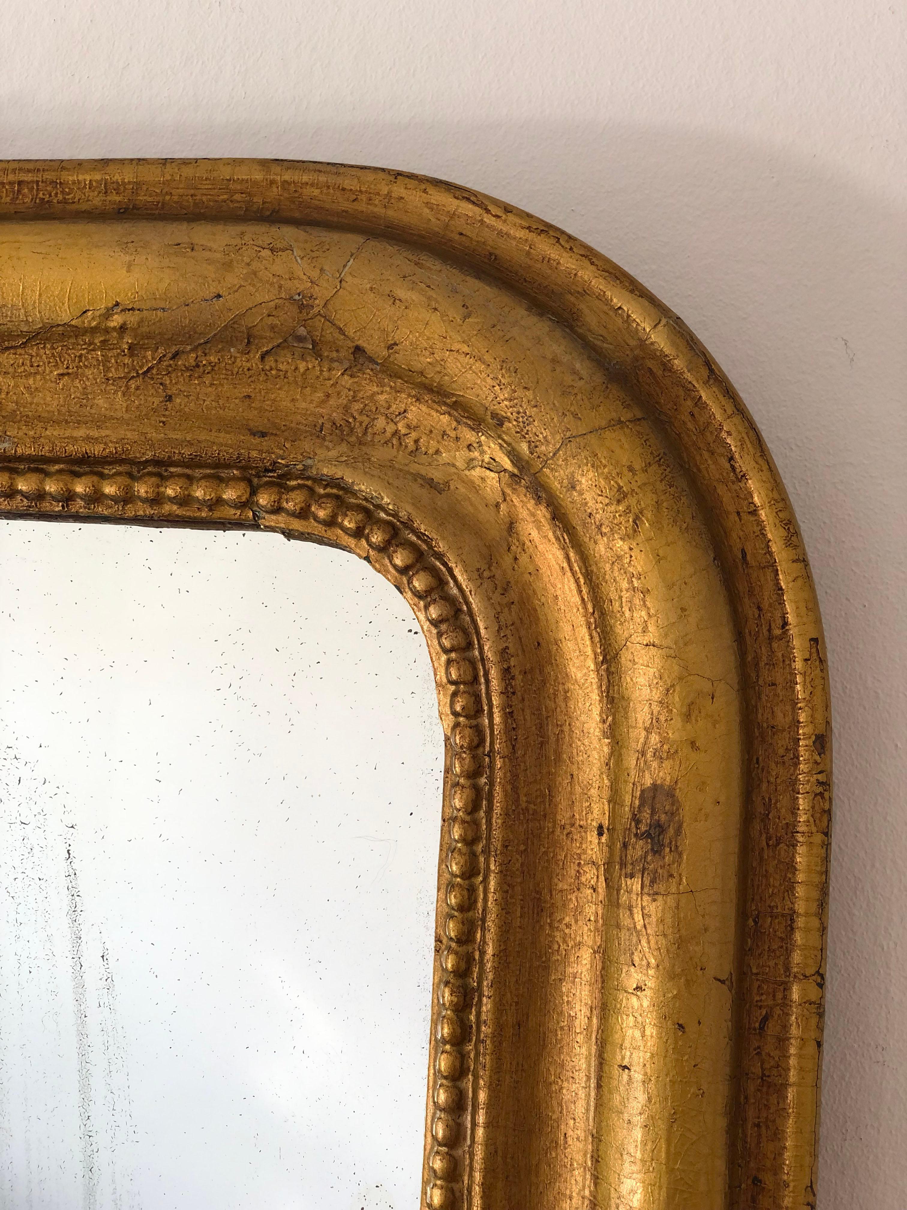 An antique Louis Philippe mirror from France, dating to the late 19th century.
With an appearance of grandeur, the carved giltwood frame features gracefully curved top corners, a beautiful worn gold leaf patina, and a delicate pearl rim. The