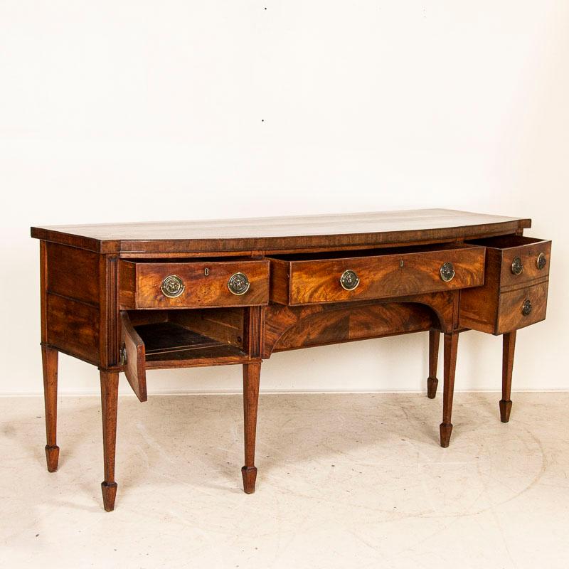 There is an understated elegance to this lovely 7' long buffet server from England. There is a deep patina to the beautiful mahogany veneer and a gentle curve graces the slightly bowed front. To the right of the long slender drawer is a drawer with