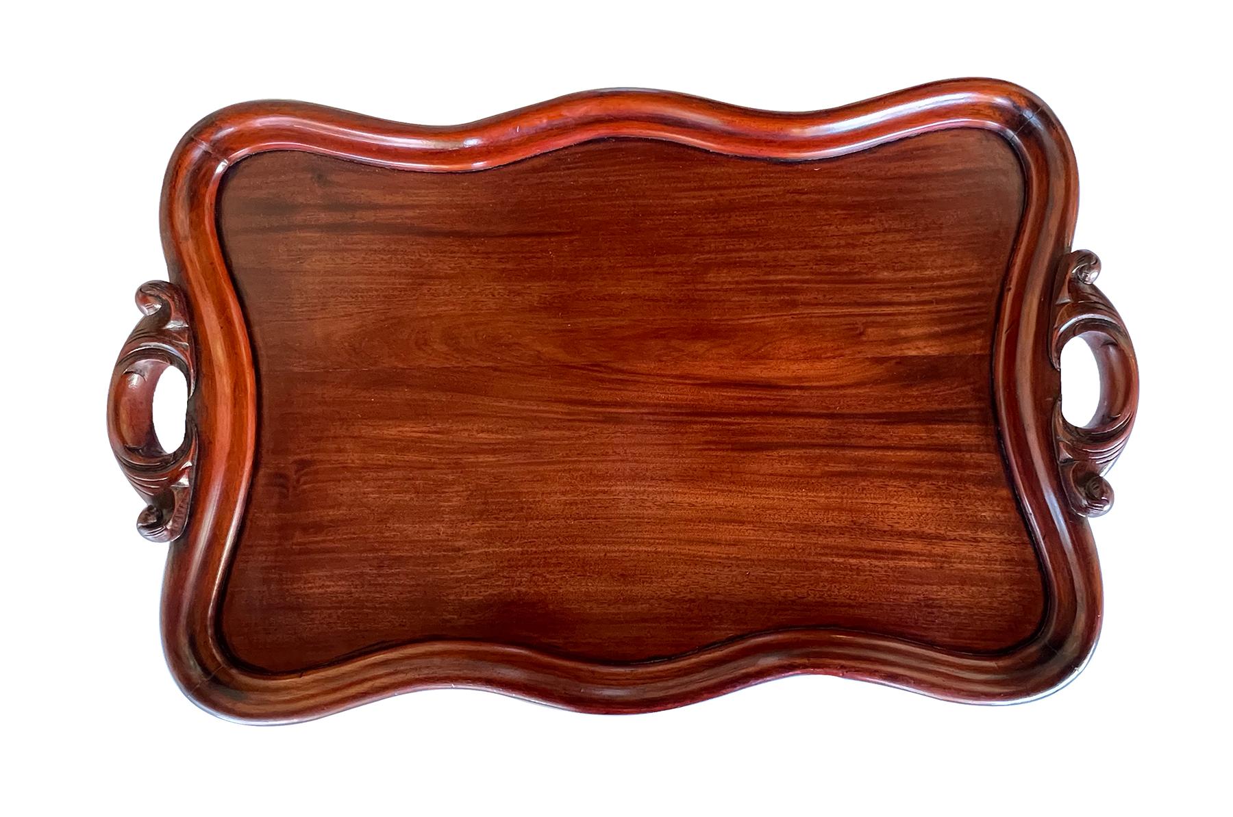 gran bandeja de caoba ricamente patinada de forma abalete con gruesa moldura perimetral conopial toda ella flanqueada por asas foliadas caladas