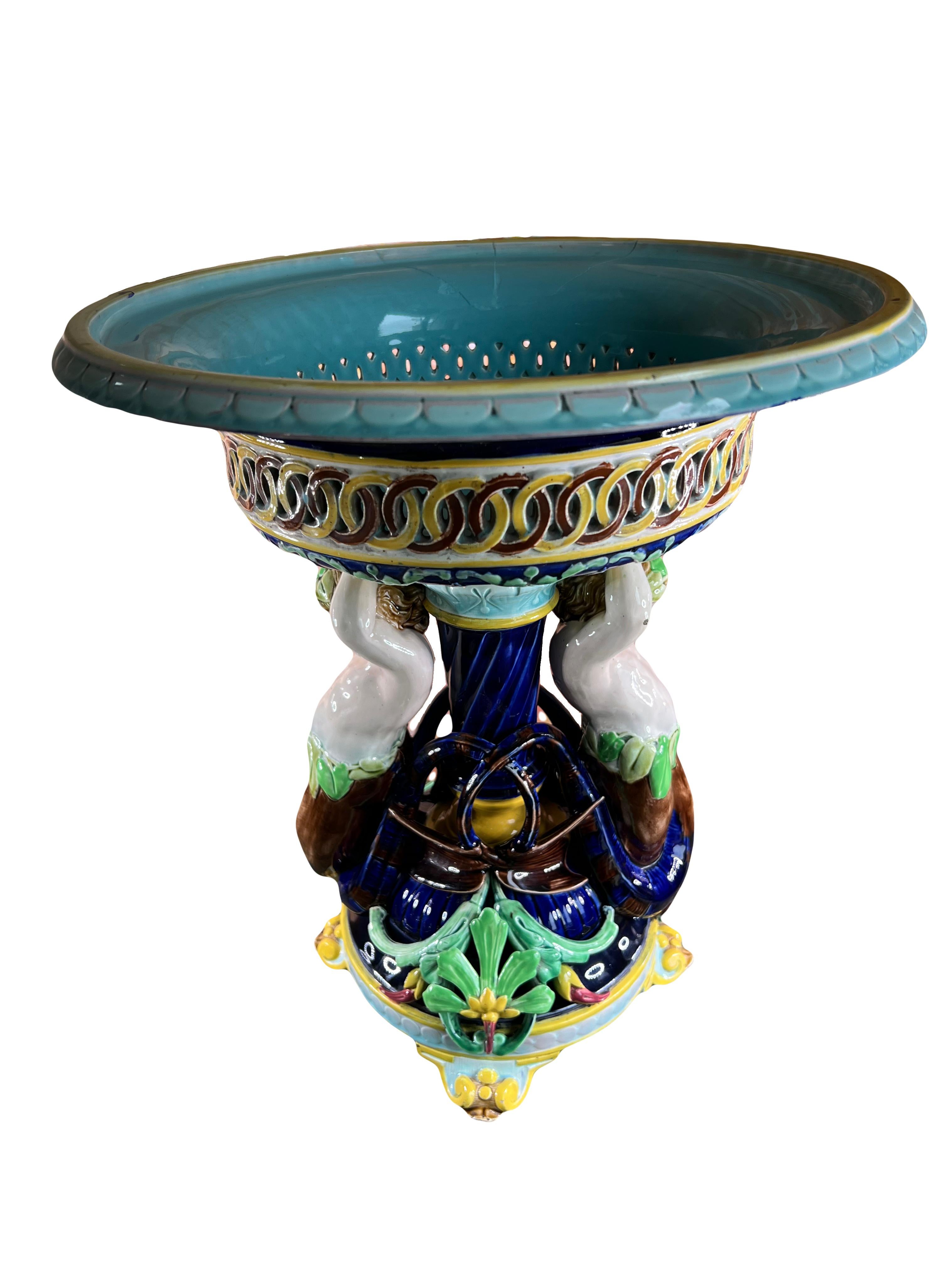 Grand bol à piédestal en majolique orné de créatures fantastiques sur la base. Ce superbe centre de table provient de la manufacture de Sarreguemines et date de la fin du XIXe siècle.

Cette impressionnante coupe est soutenue par des putti, des
