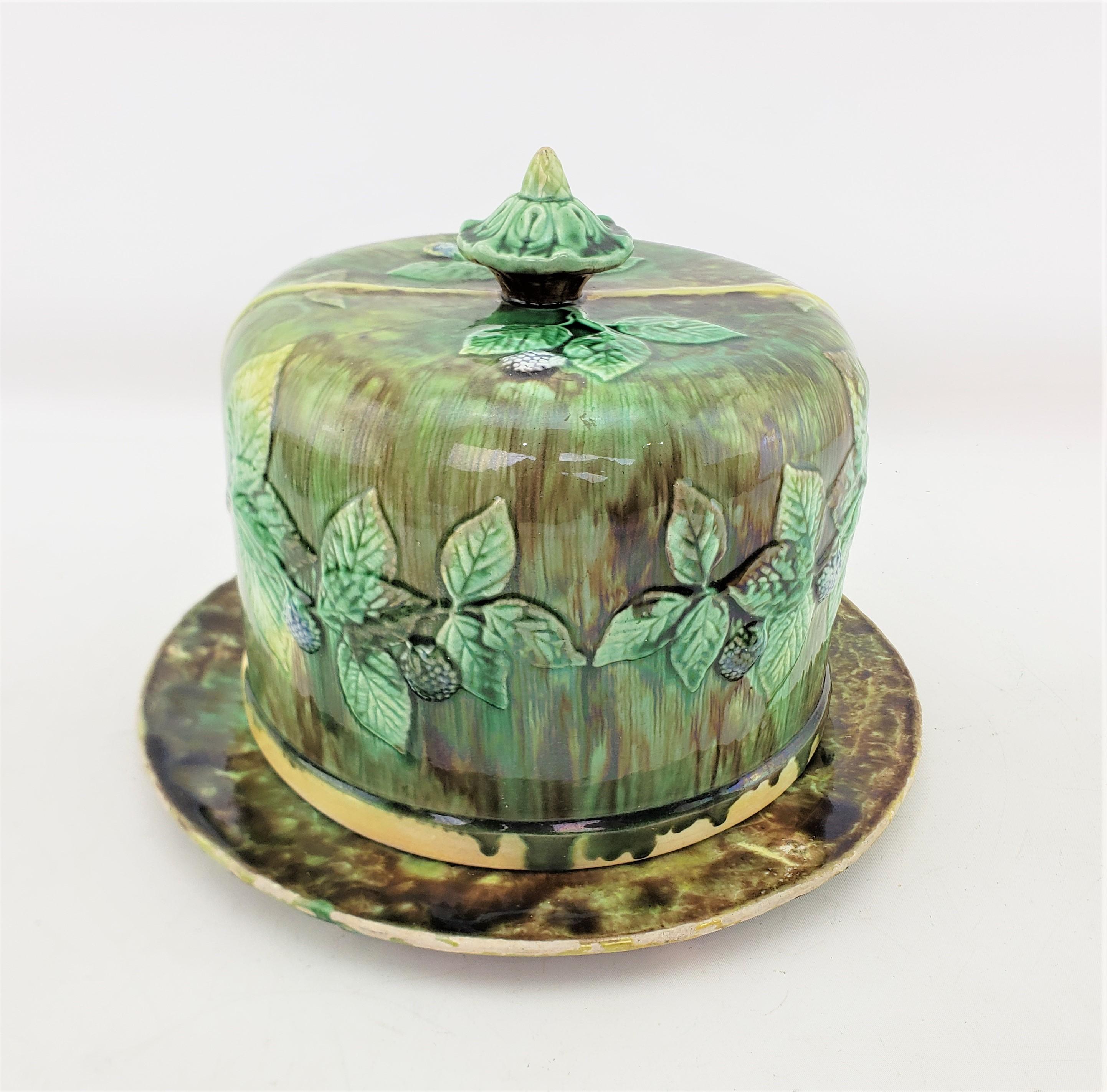 This antique cheese server or dome is unsigned, but presumed to have originated from the United States and dates to approximately 1880 and done in the period Victorian style. This large cheese dome is composed of majolica with a deep green and brown