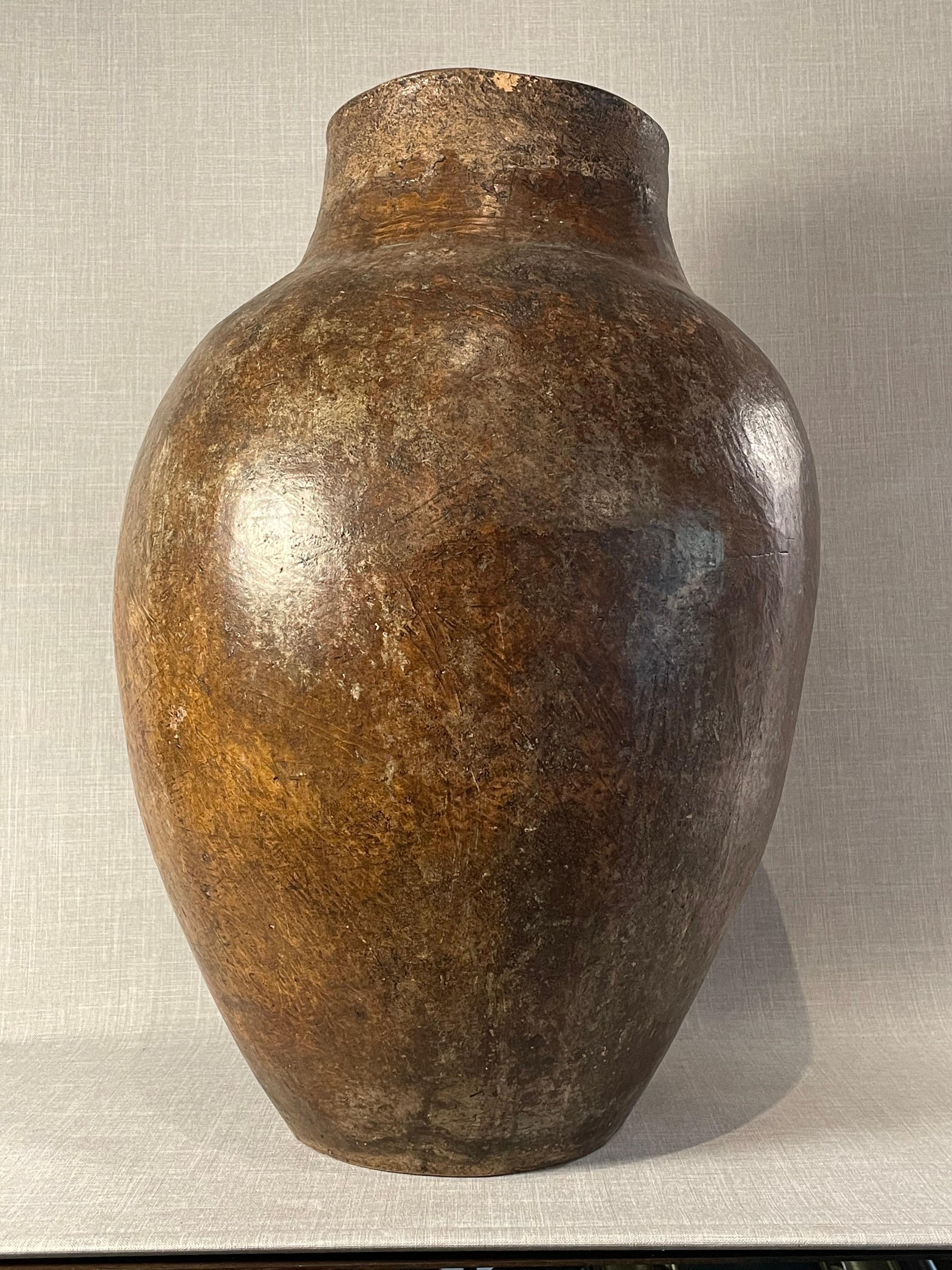 This exceptional antique Mediterranean terracotta storage jar exudes a timeless rustic charm with its commanding presence and deep, naturally aged patina. Hand-thrown from earthen clay, the vessel displays a beautifully bulbous body tapering