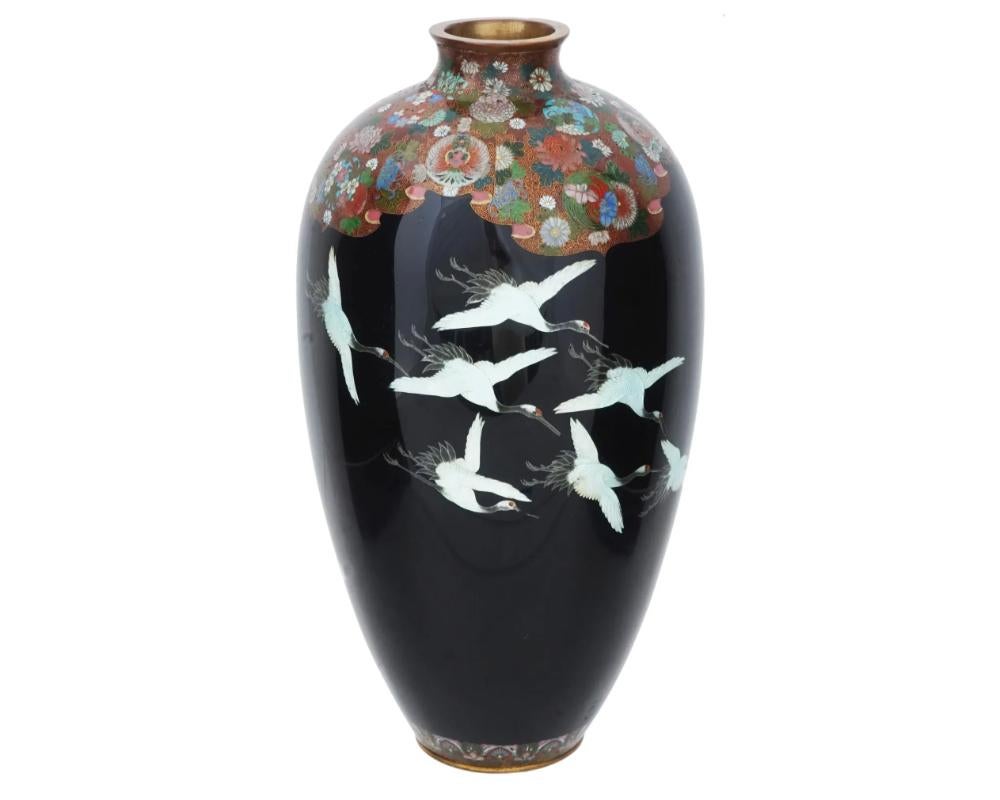 A large antique Japanese, Meiji era, Silver wire enamel over brass copper vase. Circa: 1900s. The urn form vase is enameled with polychrome images of cranes made in the Cloisonne technique on a black ground. The upper part and the neck of the ware
