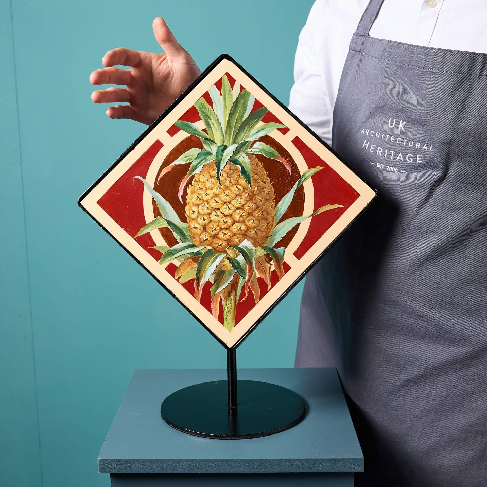 Un grand carreau ancien de Minton Hollins & Co représentant un ananas.

Présenté sur un présentoir en acier fait sur mesure, ce panneau de carreaux peints à la main représente un ananas vibrant sur une tige sur un fond de terre cuite et de