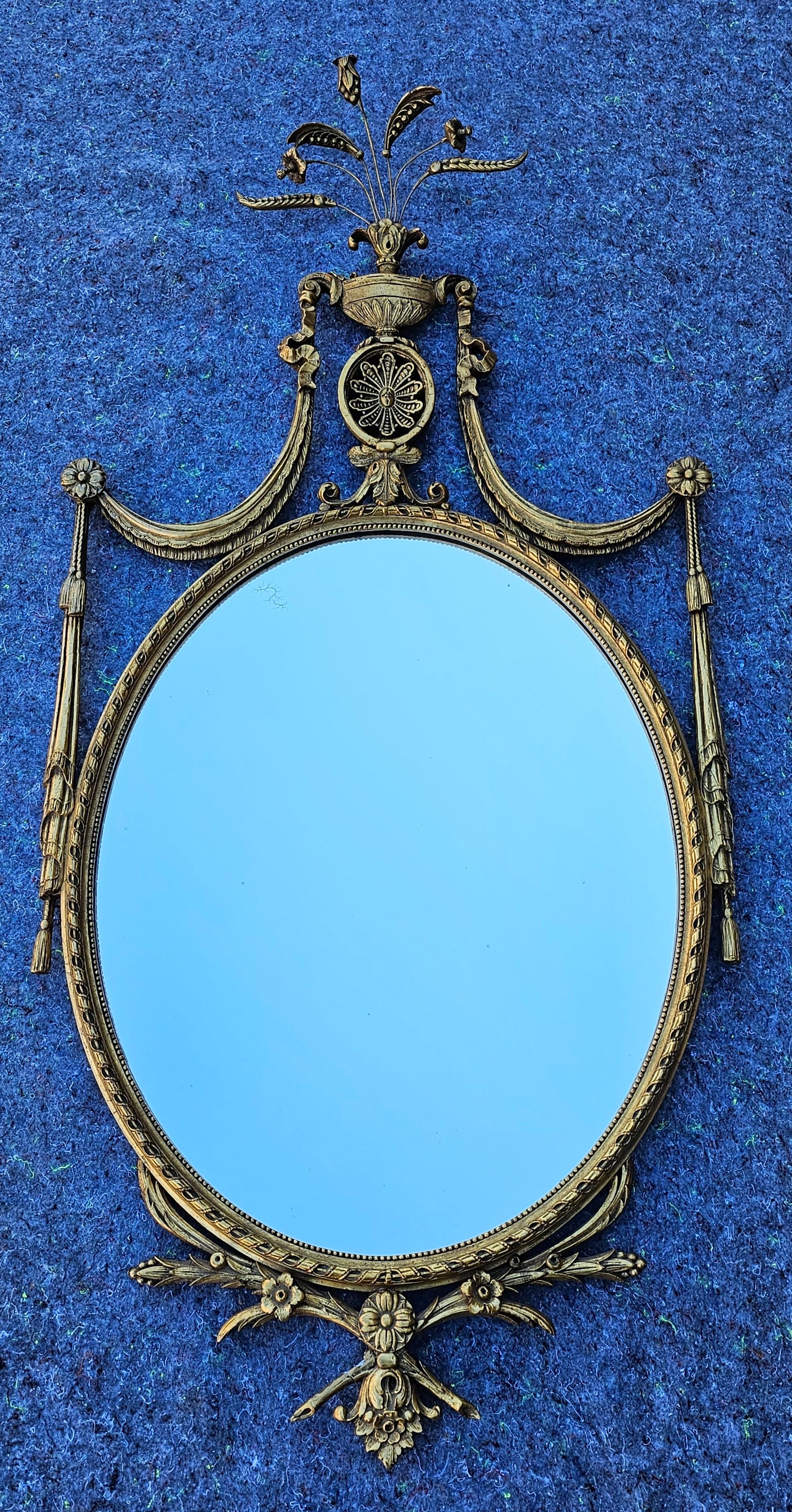Add refined elegance, luxury, and sophistication to any space with this magnificent antique British Regency era Adam style carved giltwood wall mirror. circa 1800

Exquisitely hand carved in the early 19th century, gessoed, water gilded finish with