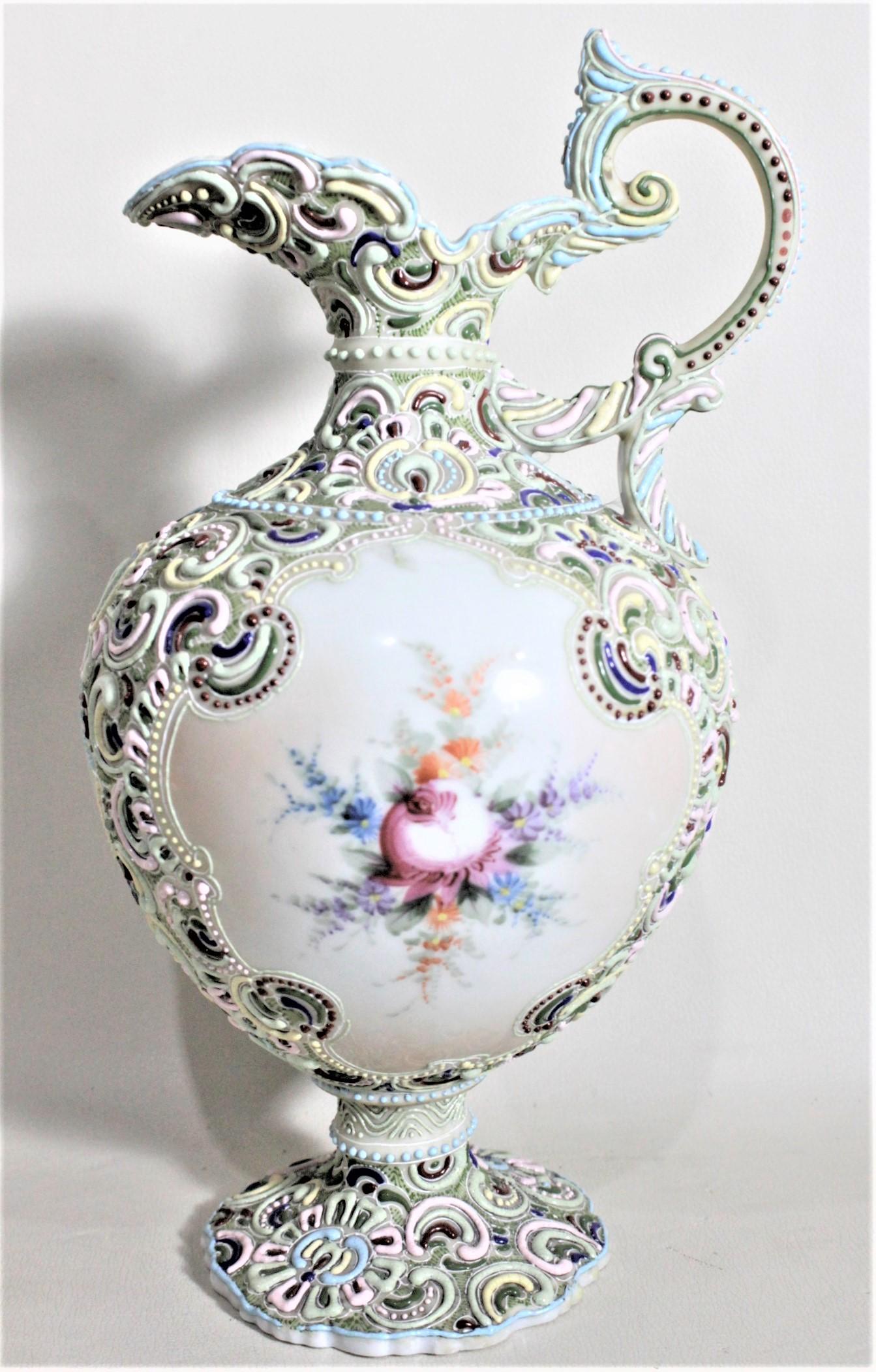 This large antique and ornately decorated ewer is unsigned, but believed to have been made by the Nippon Company of Japan in approximately 1900 in an Anglo-Japanese style. The pitcher is very ornately decorated with raised or moriage decoration in