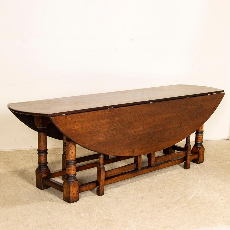 This large gate leg dining table is also known as an English wake table with drop leaves. Notice the attractive patina of the dark oak, aged and naturally distressed over generations of use. The large oval shaped top has 2 drop leaves, so when