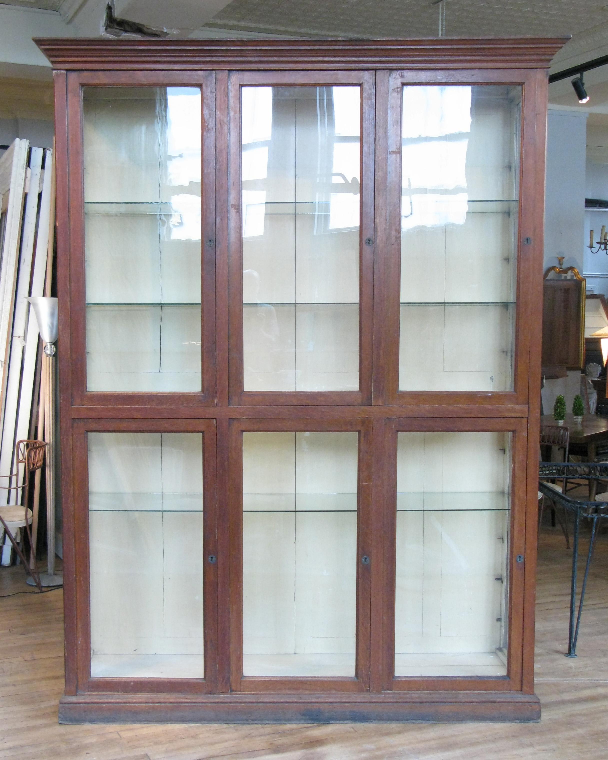 A very handsome antique late 19th century display cabinet with an oak case and glass doors and side lights. The interior back in its original pale cream color, and with four full width glass shelves.