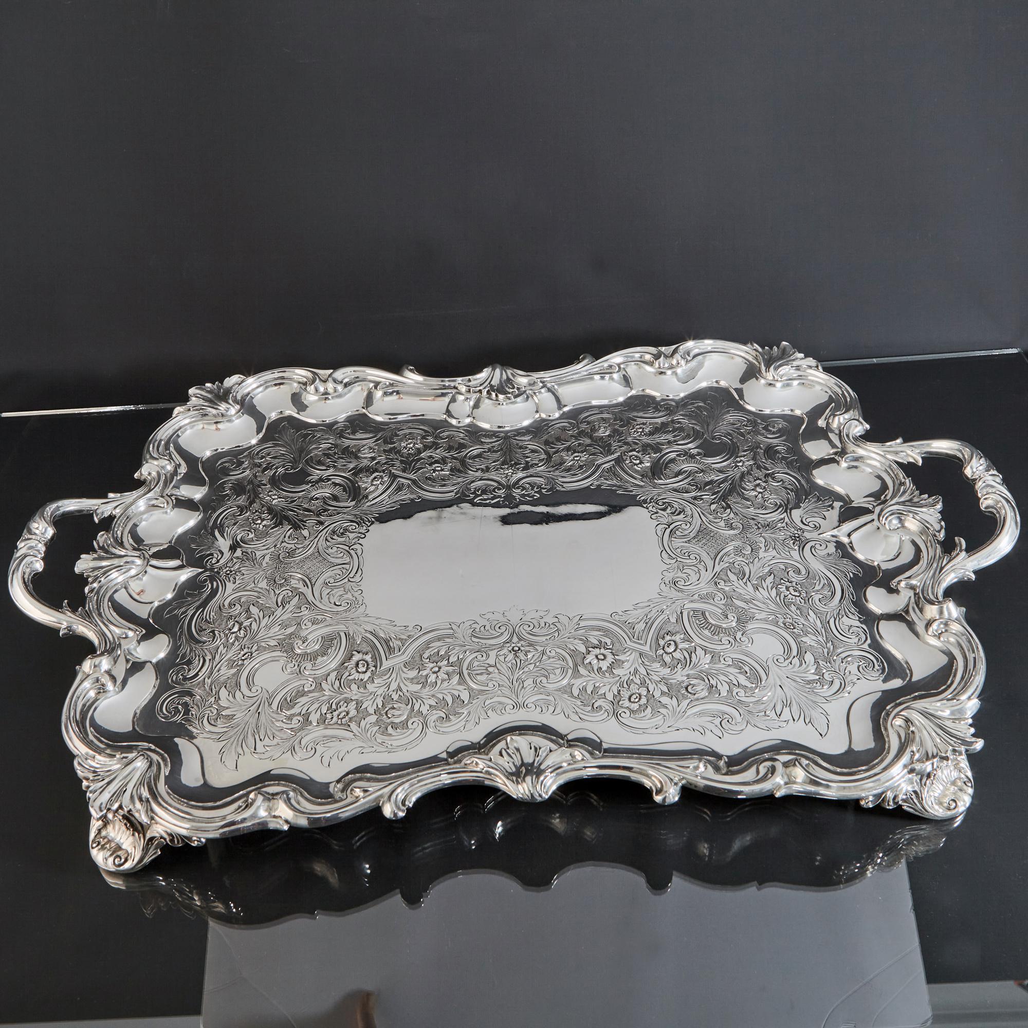 Magnificent and fine oblong antique silver tray with shaped leaf and scroll border and scroll handles. The surface of this tray is hand chased with beautifully detailed flower heads, leaves and scrolls against a mottled background, and surrounding a