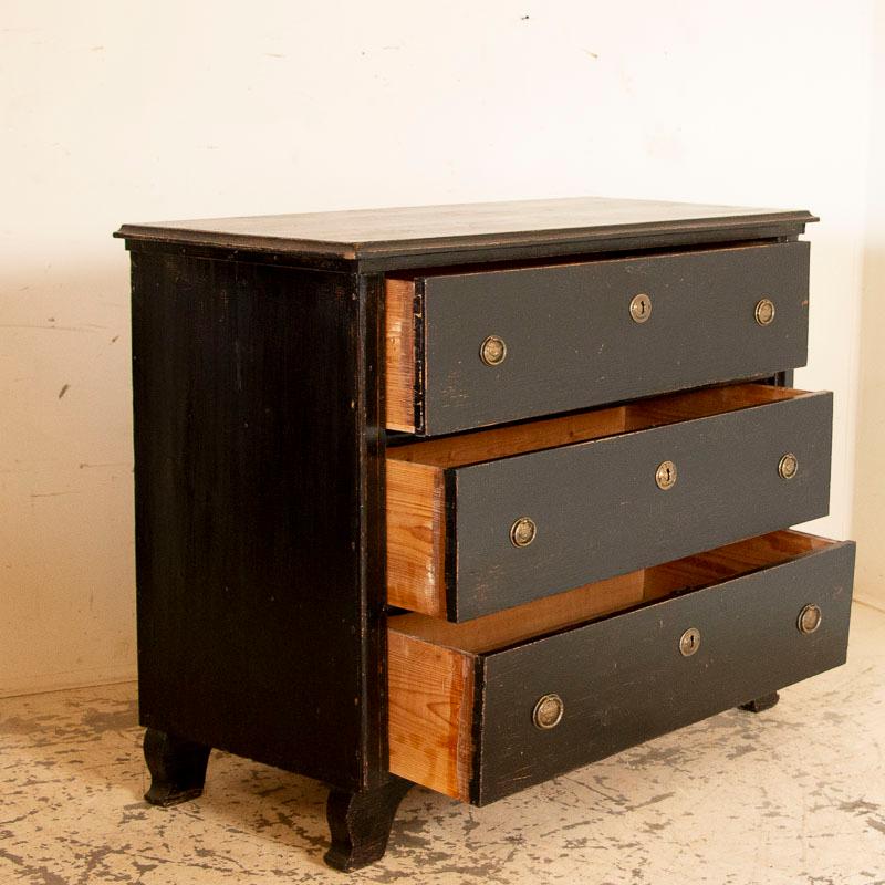 The impressive size and original black painted finish combine with inviting effect in this very large chest of 3 drawers. The black paint has been worn and distressed over time, revealing scratches, dings, and areas so worn the natural pine wood