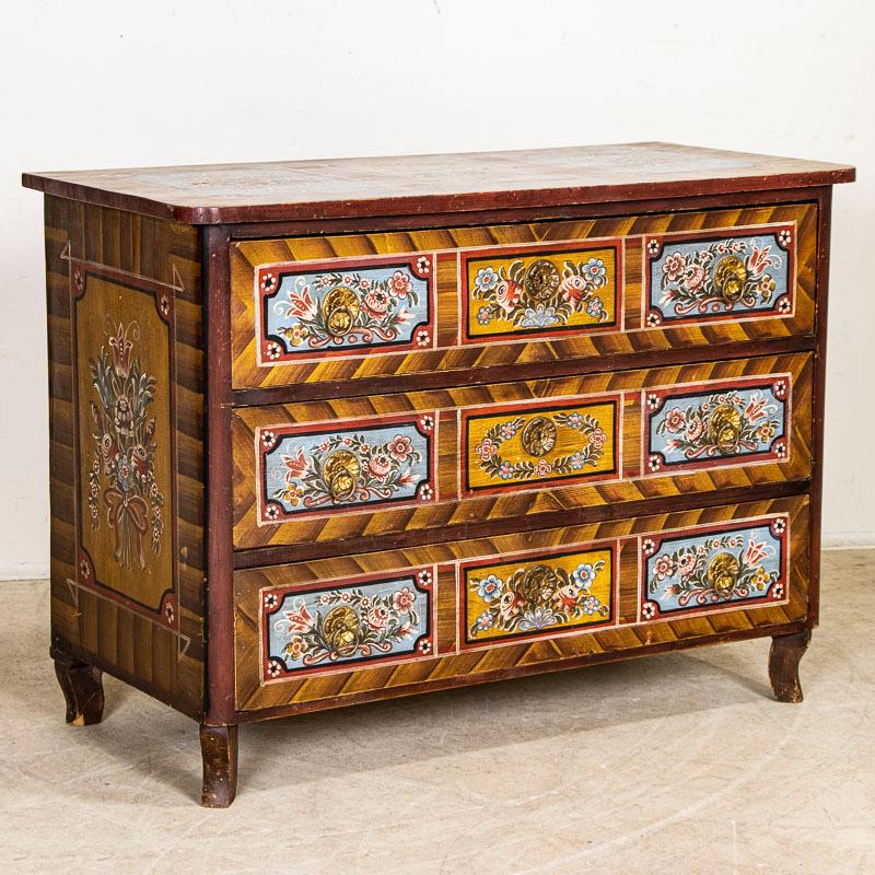 The vibrant colors are all original on this painted antique chest of 3 drawers from Hungary. The floral embellishments were traditional Folk Art designs during the 1800s. The whimsical flowers and bright colors create a cheerful feel in many Eastern