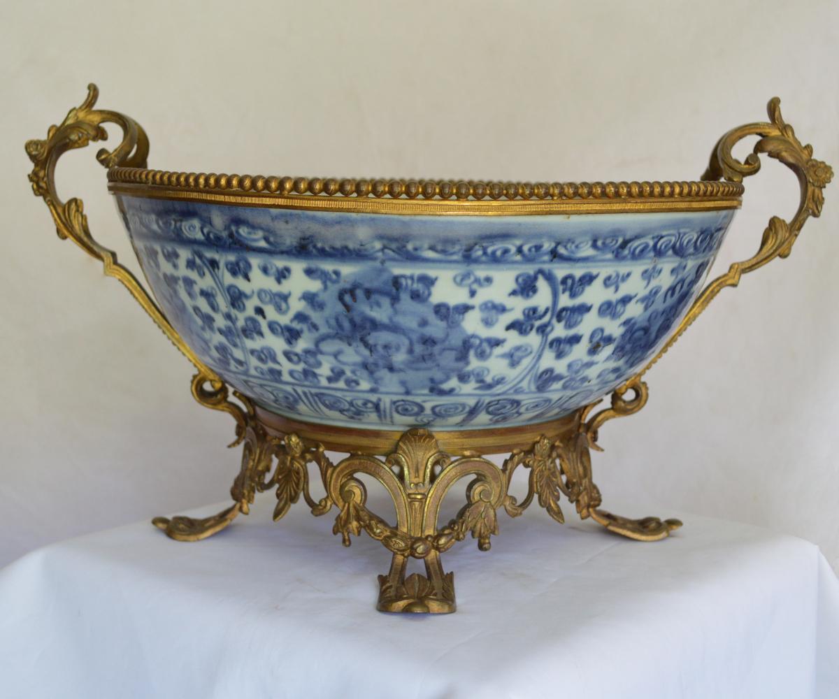 This unusual piece is comprised of a Chinese Ming dynasty blue and white porcelain bowl with peony blooms on a back ground of flowers surround a central medallion with a French gold gilt ormolu bronze mount frame from the 19th century. This effort