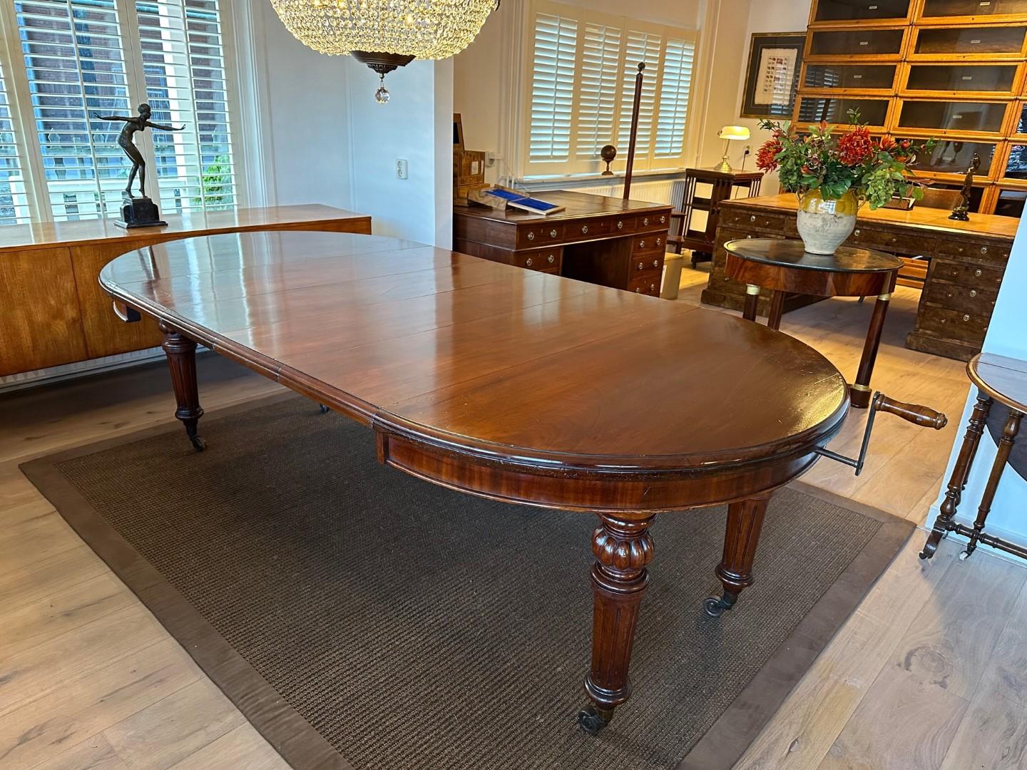 Beautiful large antique oval English dining room table with 4 extra original leaves. The table is from the early Victorian period. It is a table that you can make larger and smaller by means of: a turning mechanism. You can turn the table apart and