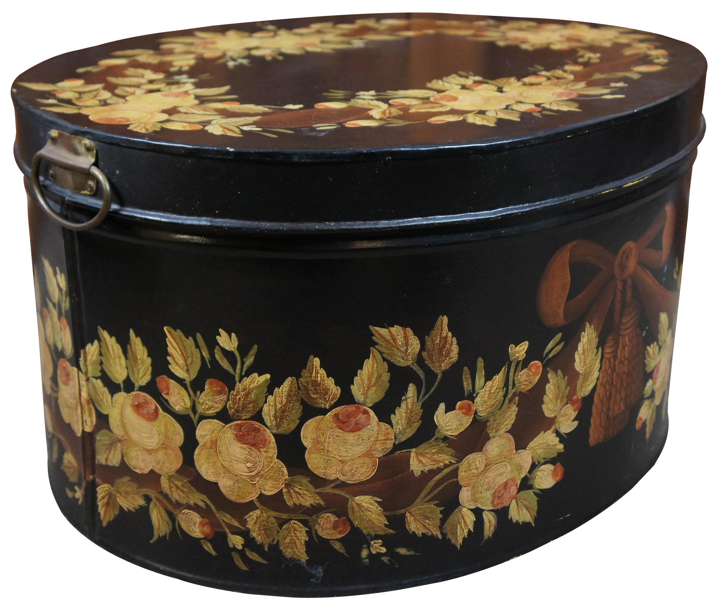 Large vintage oval toleware box or bin with painted metal base, handles, and wooden lid, painted in black with yellow roses in a wreath pattern with a neoclassical bow with tassles; interior painted red. Measure: 23