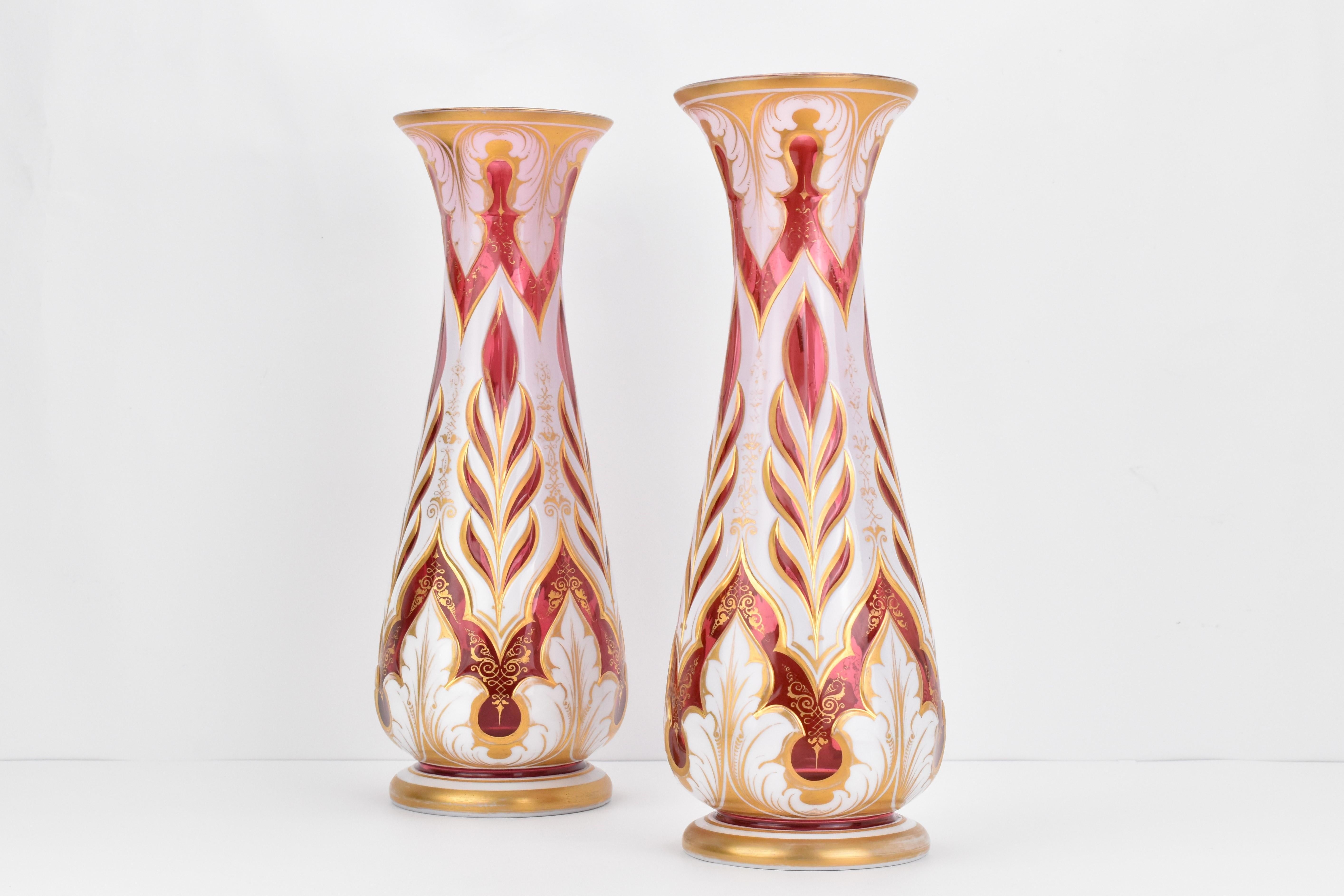 Cette superbe paire de vases en verre a été fabriquée dans la Bohemia du XIXe siècle, centre de production de verre mondialement connu.

Le corps de chaque vase est en verre cranberry, sur lequel a été appliquée une couche de verre opalin blanc

La