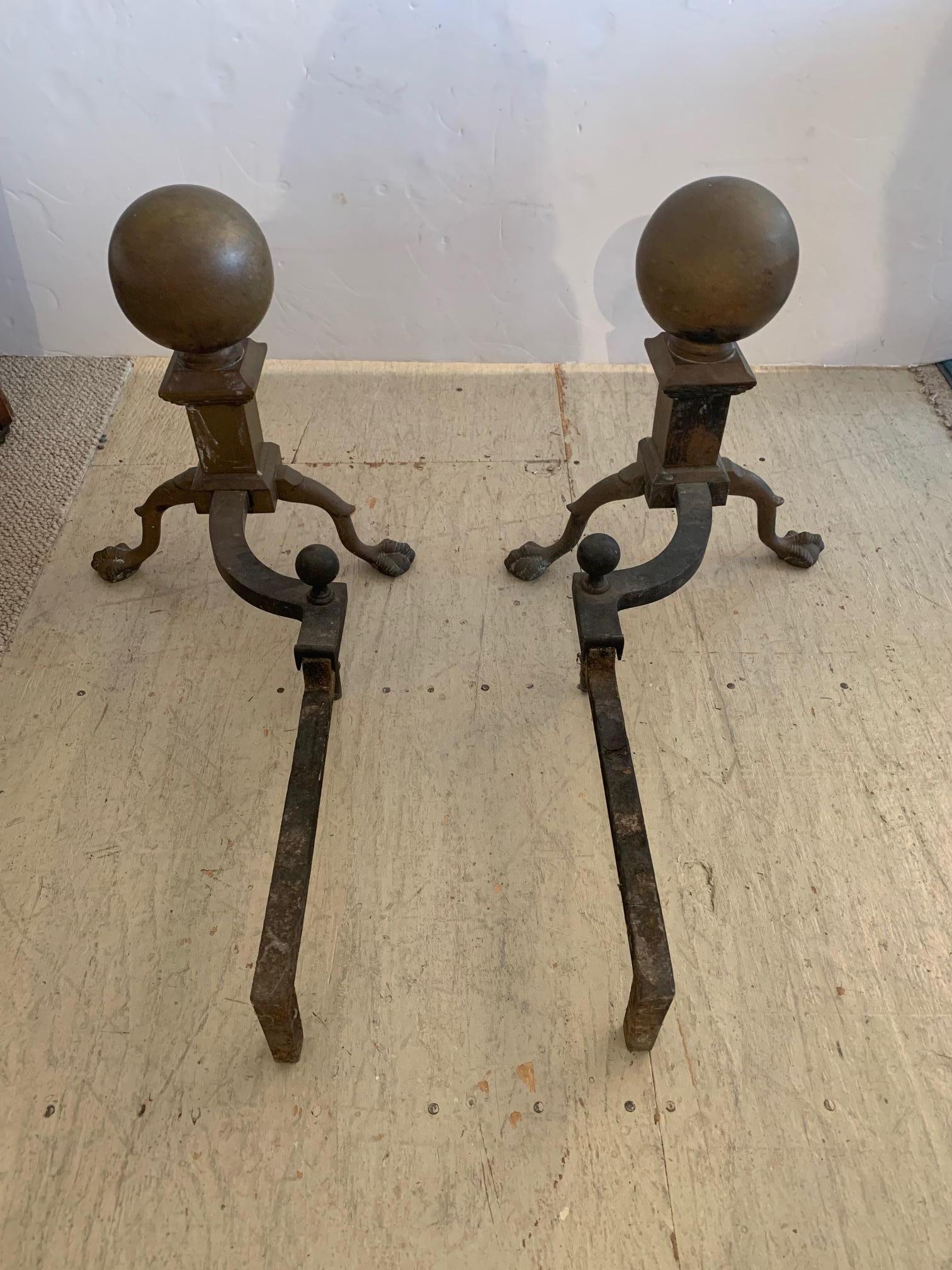 Handsome pair of antique brass and iron cannonball design andirons having brass fenders and ball and claw feet.