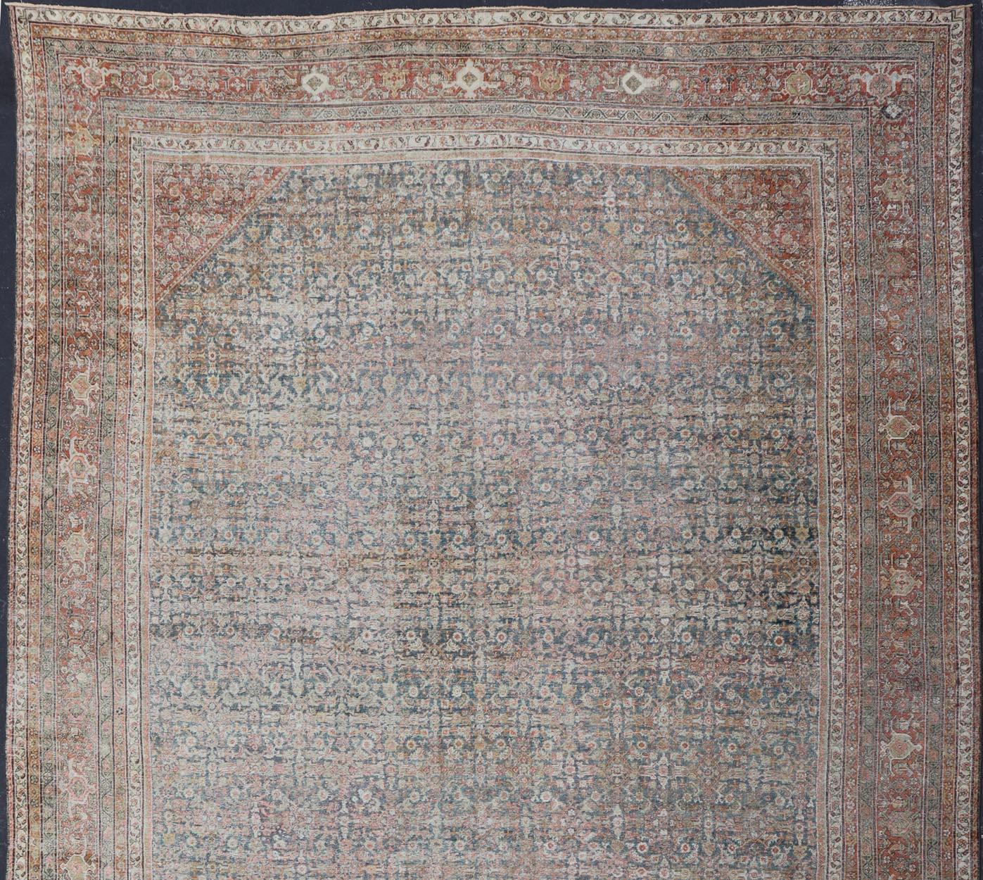 This impressive antique distressed Persian Sultanabad rug features a superb all-over Herati and sub-geometric design throughout the entirety of the piece. The entire body is enclosed by complementary, multi-tiered borders. The rug is rendered in