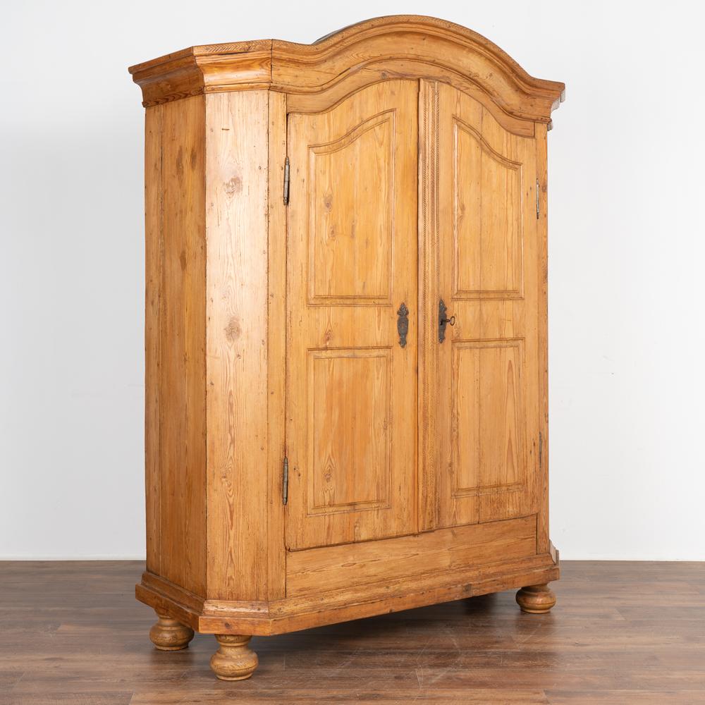 It is the captivating deep aged patina of the warm pine that captures one's attention in this lovely and spacious armoire.
Note the many hand carved and patterned hash marks that decorate the crown and vertically along the door.
The old lock and