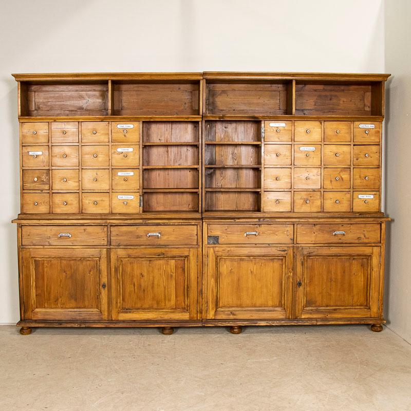 This amazing pine bookcase first served in a retail store as a pharmacy apothecary in the late 1800's. Notice the labels for medications and ingredients that still remain on some of the many drawers. This large wall unit is built in 4 sections,