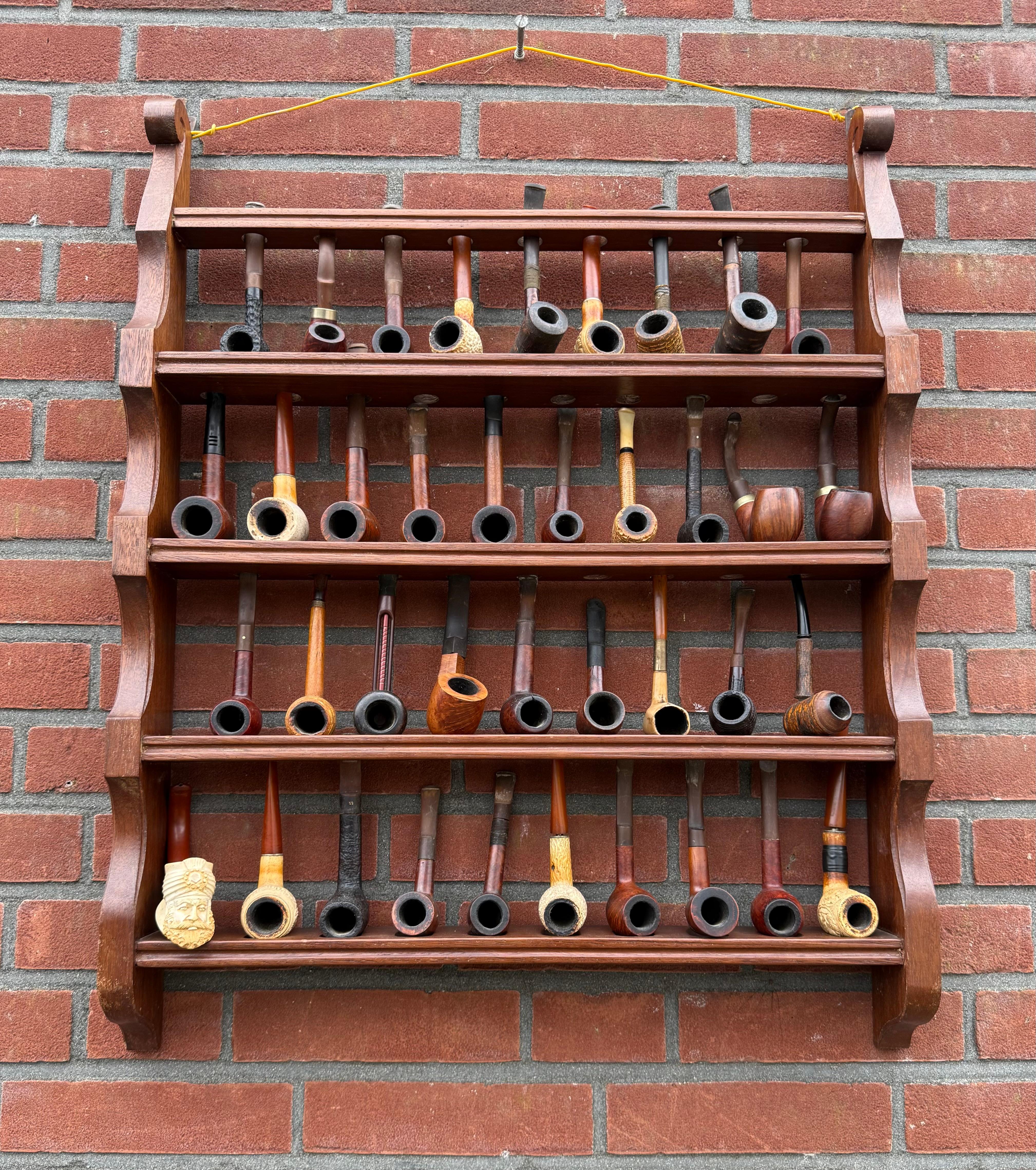 Antique oak pipe wall rack and nutwood table pipe stand/holder with antique/vintage pipe collection.

This beautiful collection for pipe smoking enthusiasts consists of a whole lot of individual pieces. First of all, there is the Arts and Crafts