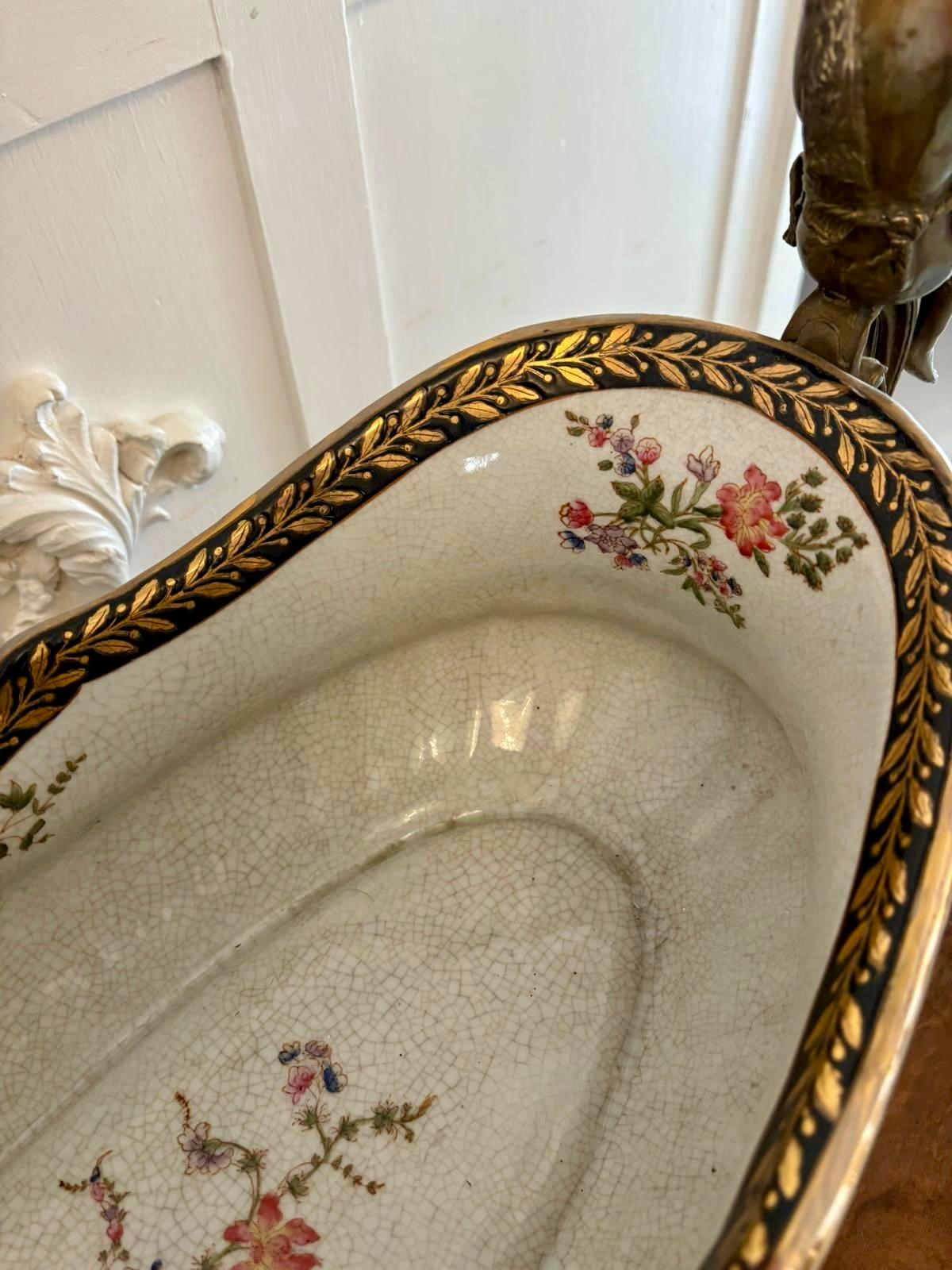 Grand centre de table antique en porcelaine et laiton comprenant un grand bol ovale en porcelaine avec un décor de guirlandes et de feuilles dans de magnifiques couleurs bleu et or, des figures de qualité en laiton orné représentant des dames